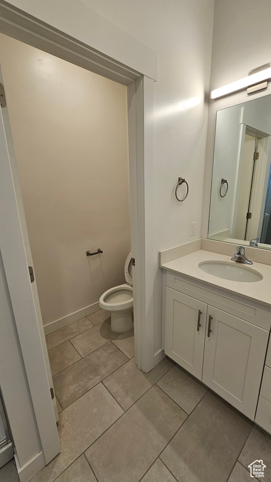 Bathroom with toilet, tile floors, and large vanity