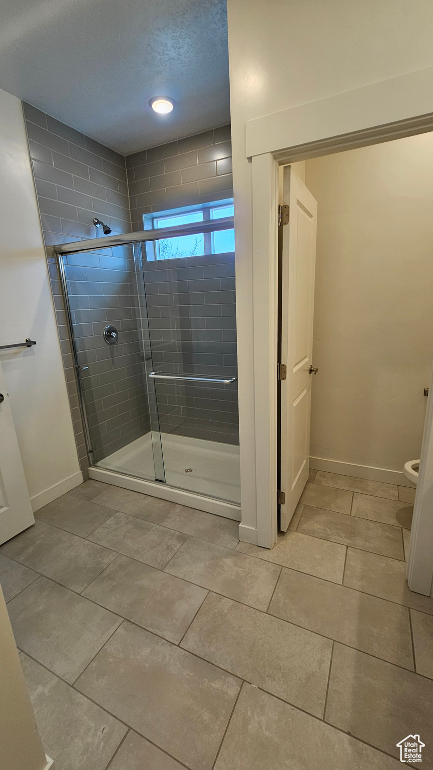 Bathroom featuring an enclosed shower, toilet, and tile floors