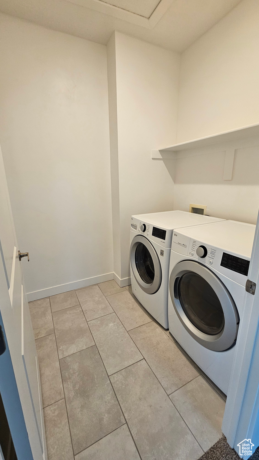 Clothes washing area featuring independent washer and dryer and light tile floors