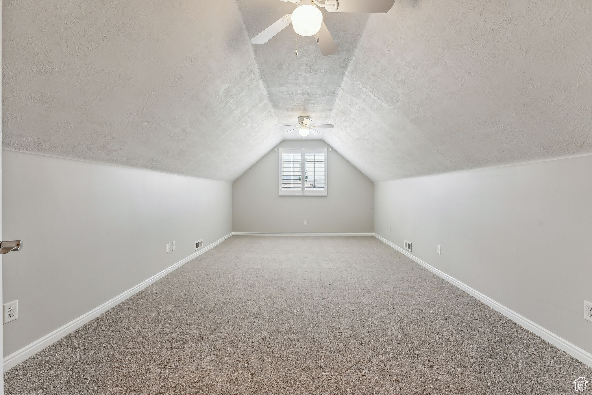 Additional living space with ceiling fan, vaulted ceiling, a textured ceiling, and carpet flooring