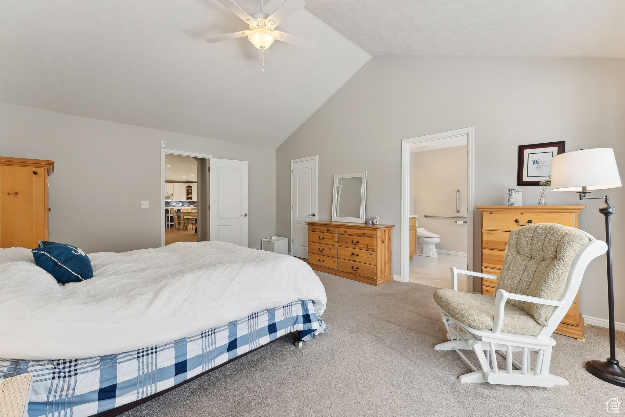 Carpeted bedroom featuring high vaulted ceiling, ceiling fan, and ensuite bath