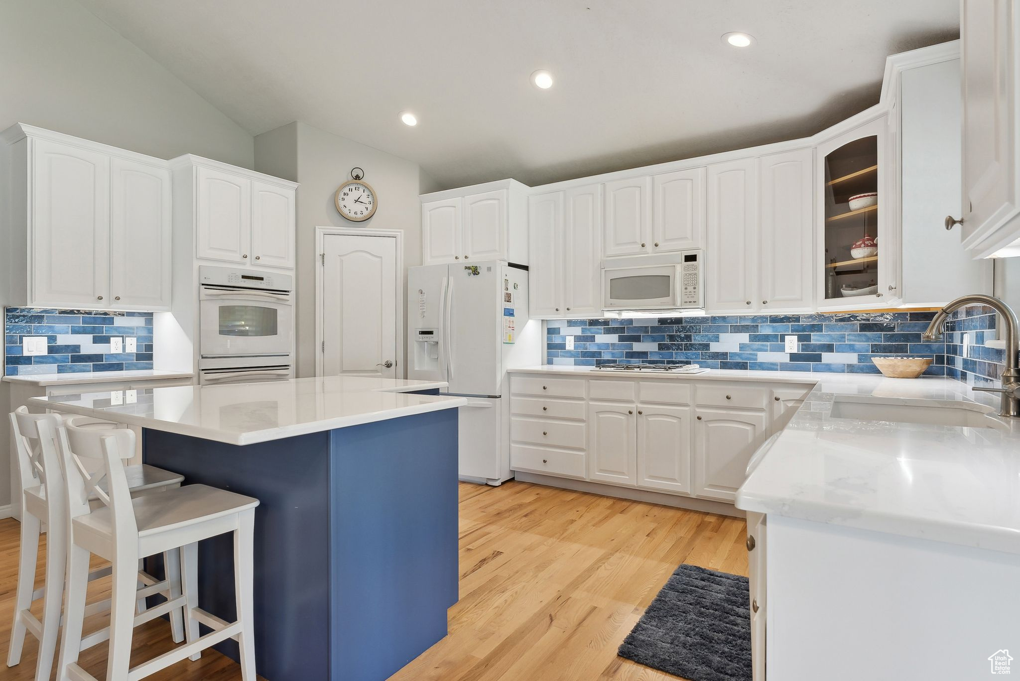 Kitchen with light hardwood / wood-style floors, white appliances, sink, tasteful backsplash, and vaulted ceiling