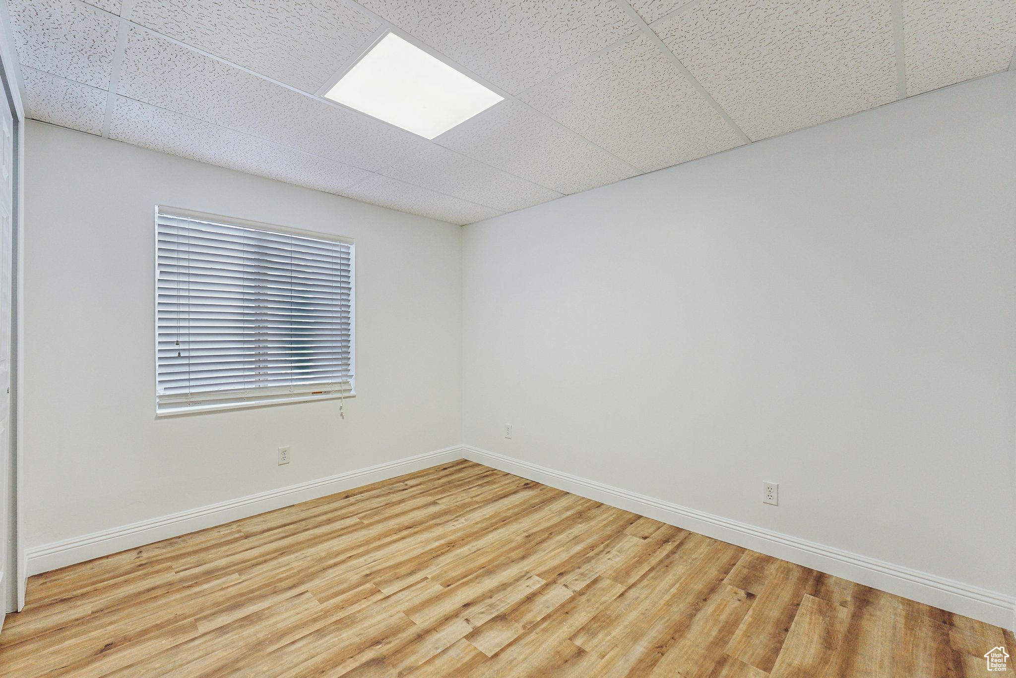 Empty room featuring light hardwood / wood-style floors and a drop ceiling