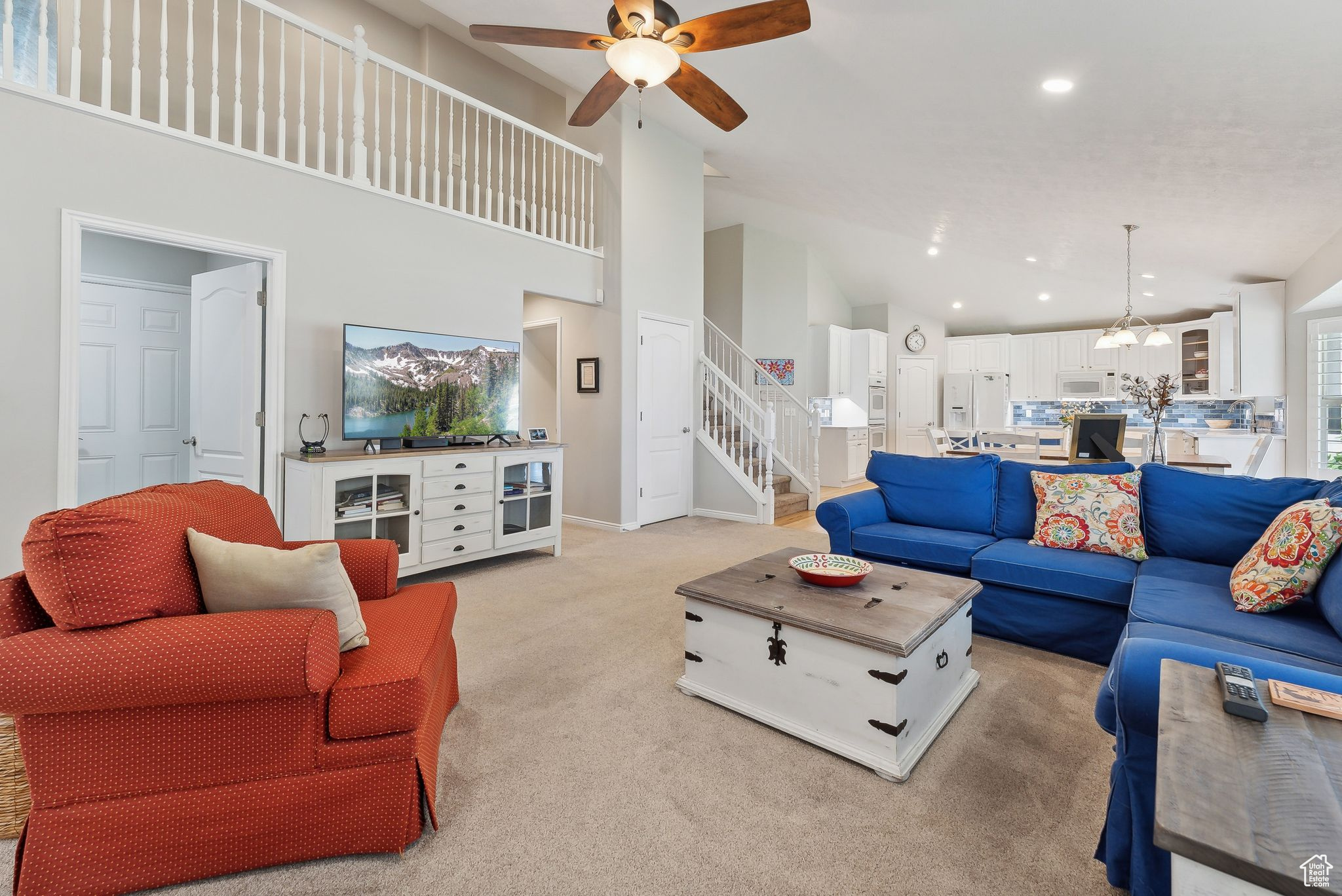 Carpeted living room featuring high vaulted ceiling and ceiling fan