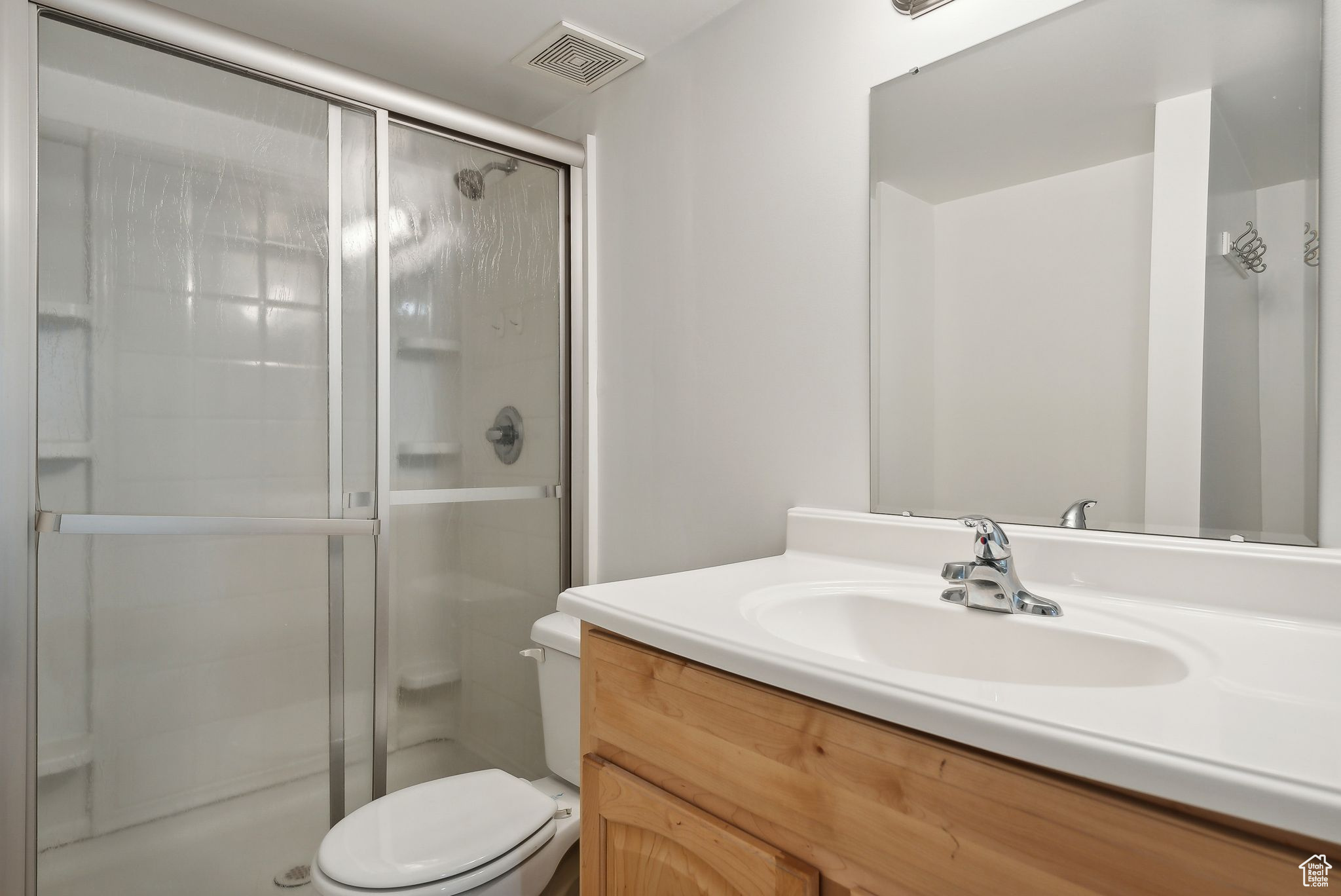 Bathroom featuring a shower with shower door, toilet, and oversized vanity