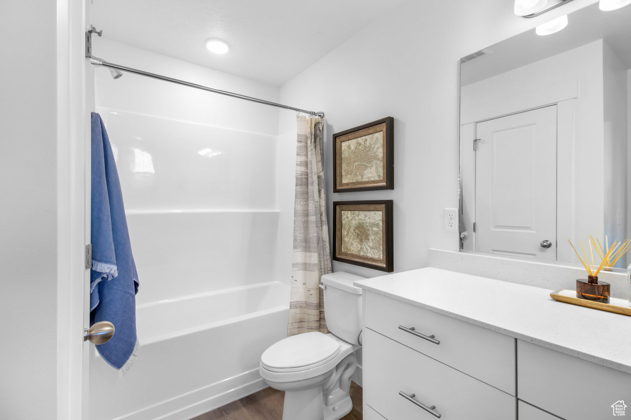 Full bathroom with shower / tub combo, toilet, hardwood / wood-style floors, and large vanity