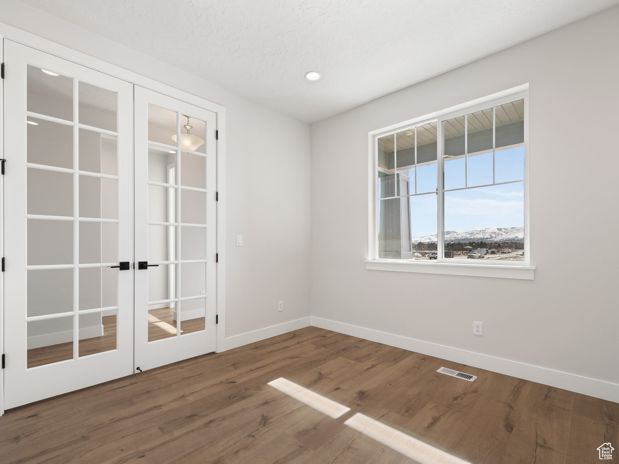 Spare room featuring wood-type flooring and french doors. This is a picture of Helena model home. Not the interior of actual home.