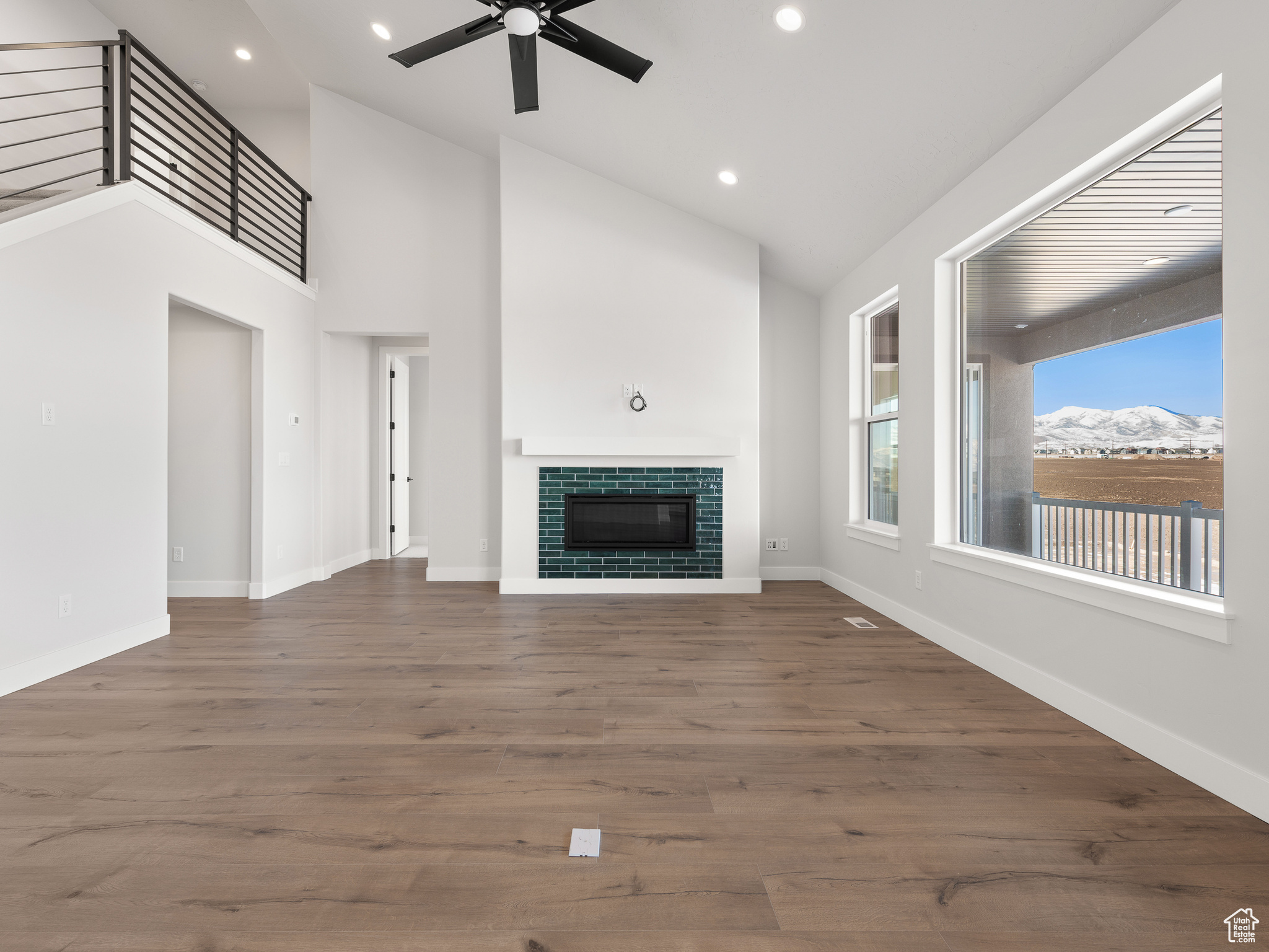 Unfurnished living room with high vaulted ceiling, ceiling fan, and dark hardwood / wood-style flooring. This is a picture of Helena model home. Not the interior of actual home.