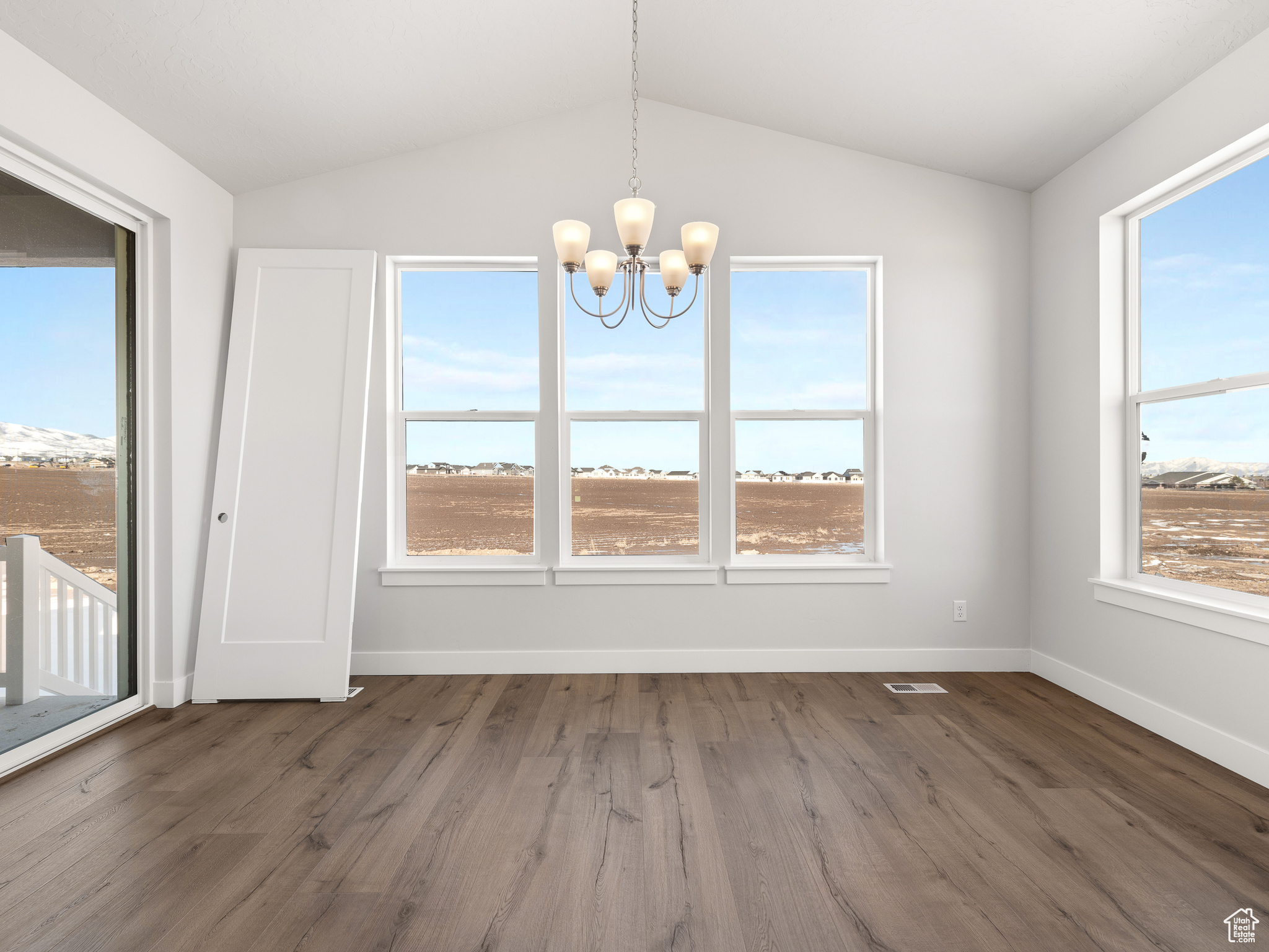 Unfurnished dining area featuring dark hardwood / wood-style flooring, lofted ceiling, and a chandelier. This is a picture of Helena model home. Not the interior of actual home.