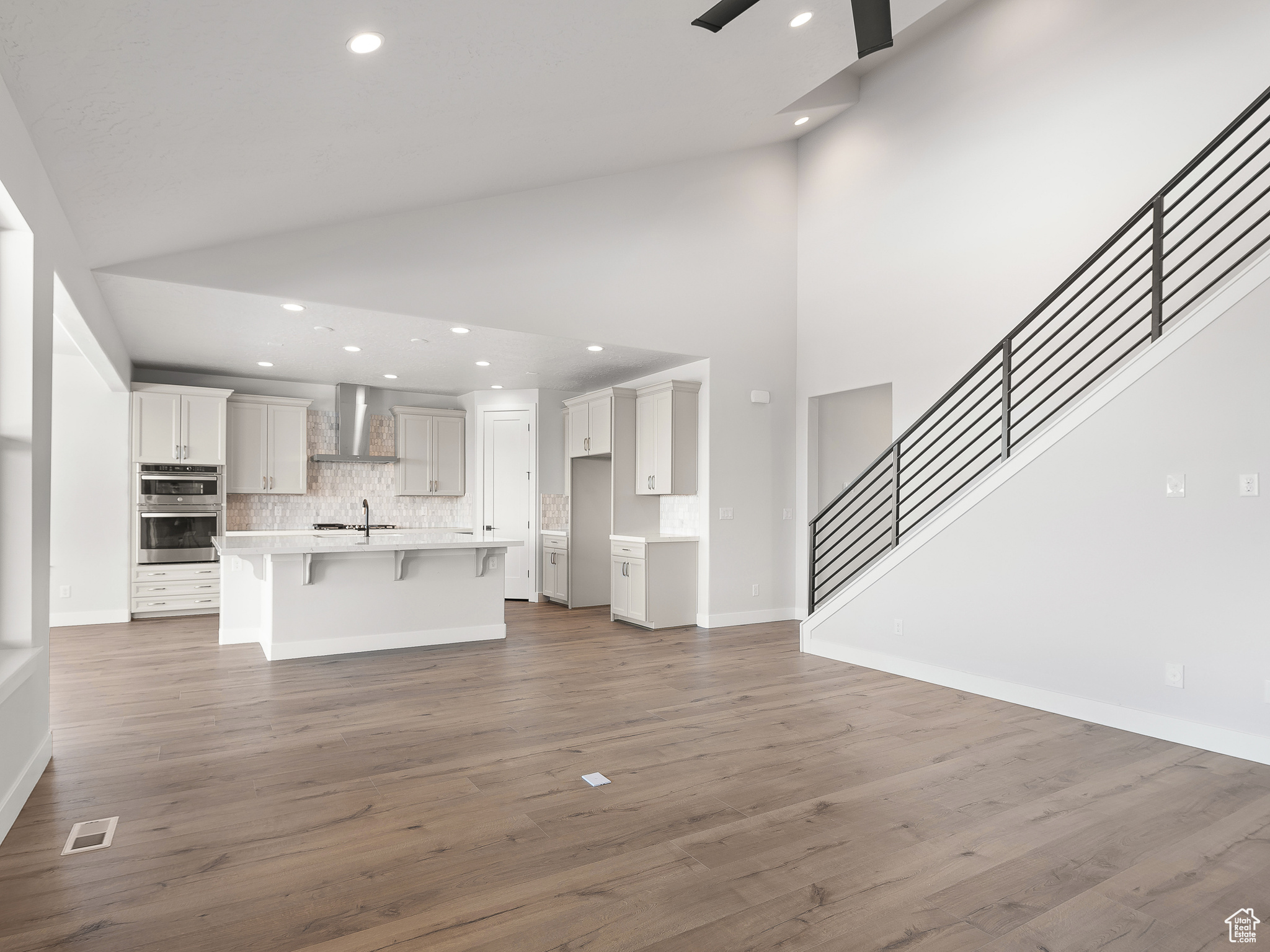 Unfurnished living room with high vaulted ceiling, sink, dark hardwood / wood-style floors, and ceiling fan. This is a picture of Helena model home. Not the interior of actual home.