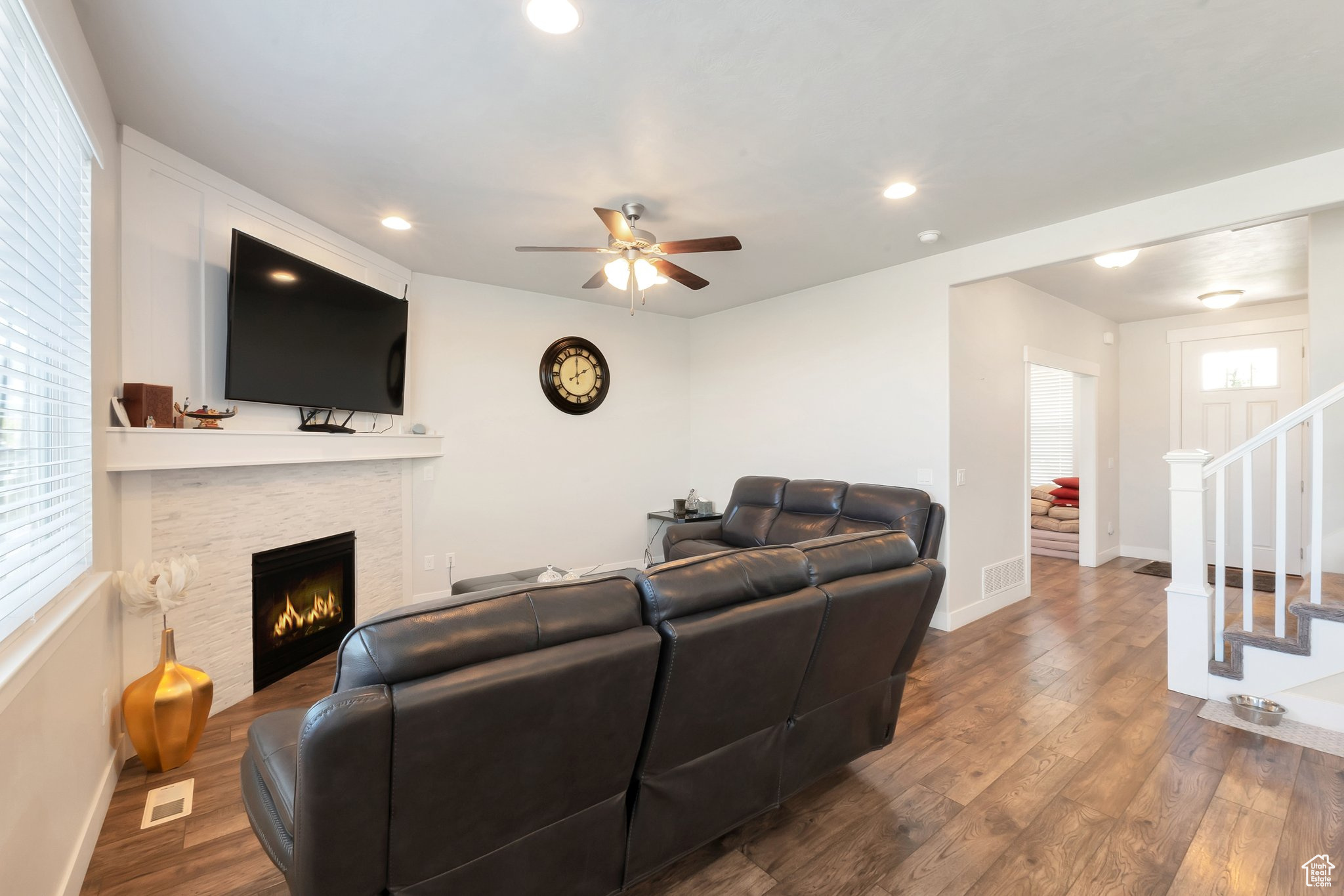 Living room with plenty of natural light, a fireplace, wood-type flooring, and ceiling fan