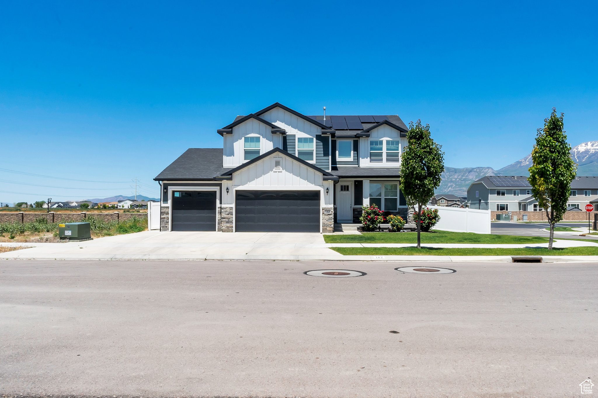 View of front facade with a front yard, a mountain view, a garage, and solar panels