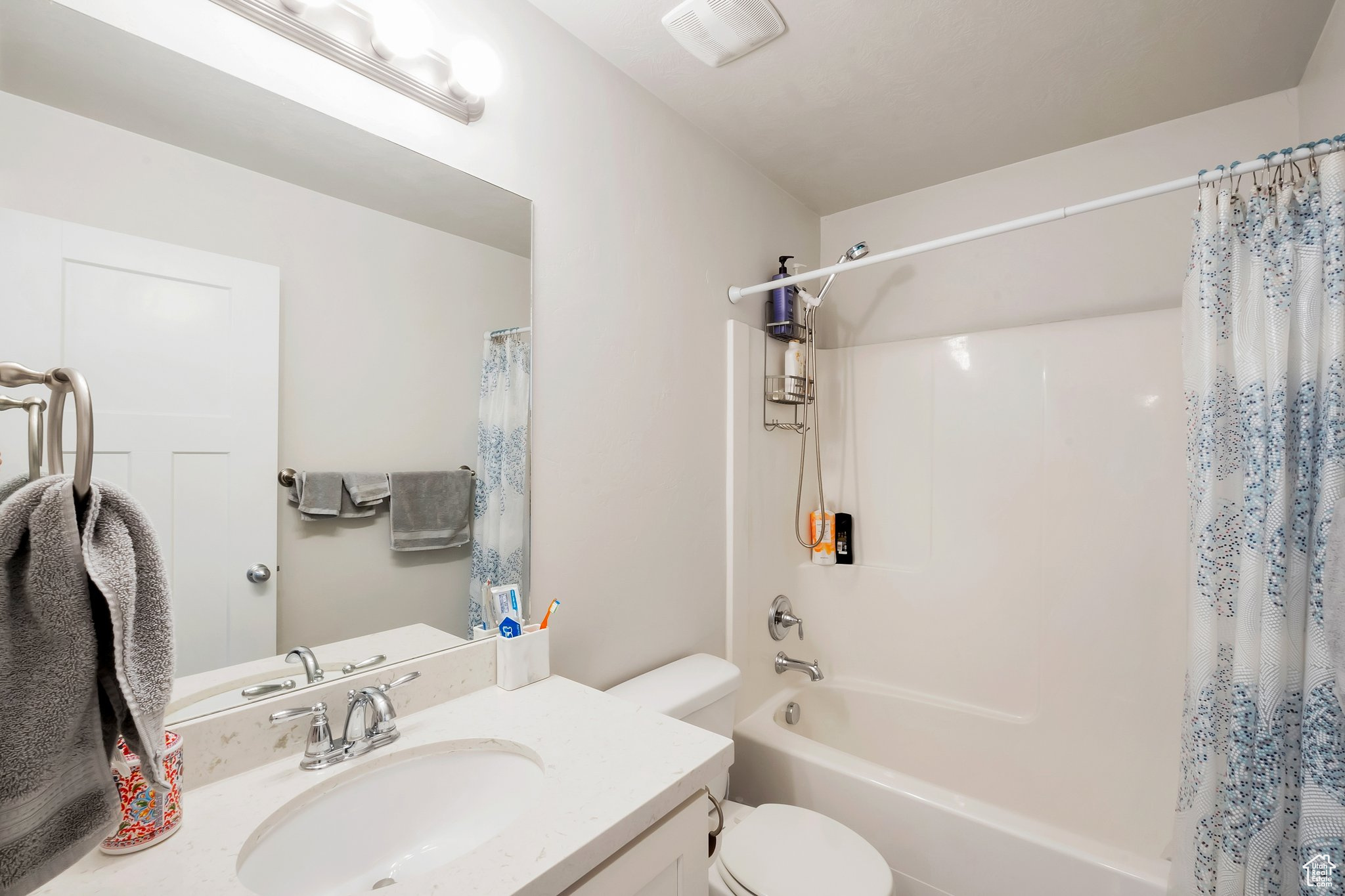 Full bathroom featuring shower / bathtub combination with curtain, vanity, and toilet