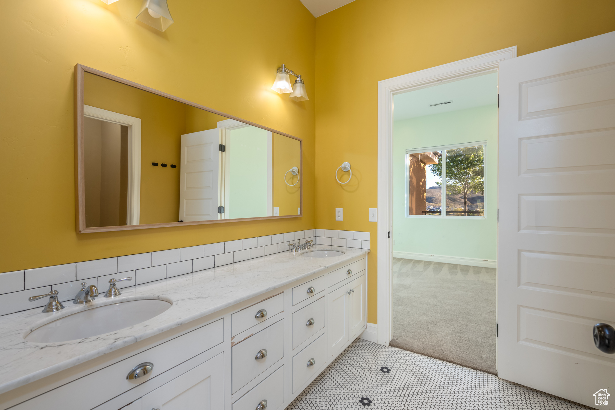 Bathroom featuring dual bowl vanity, tile flooring, and tasteful backsplash