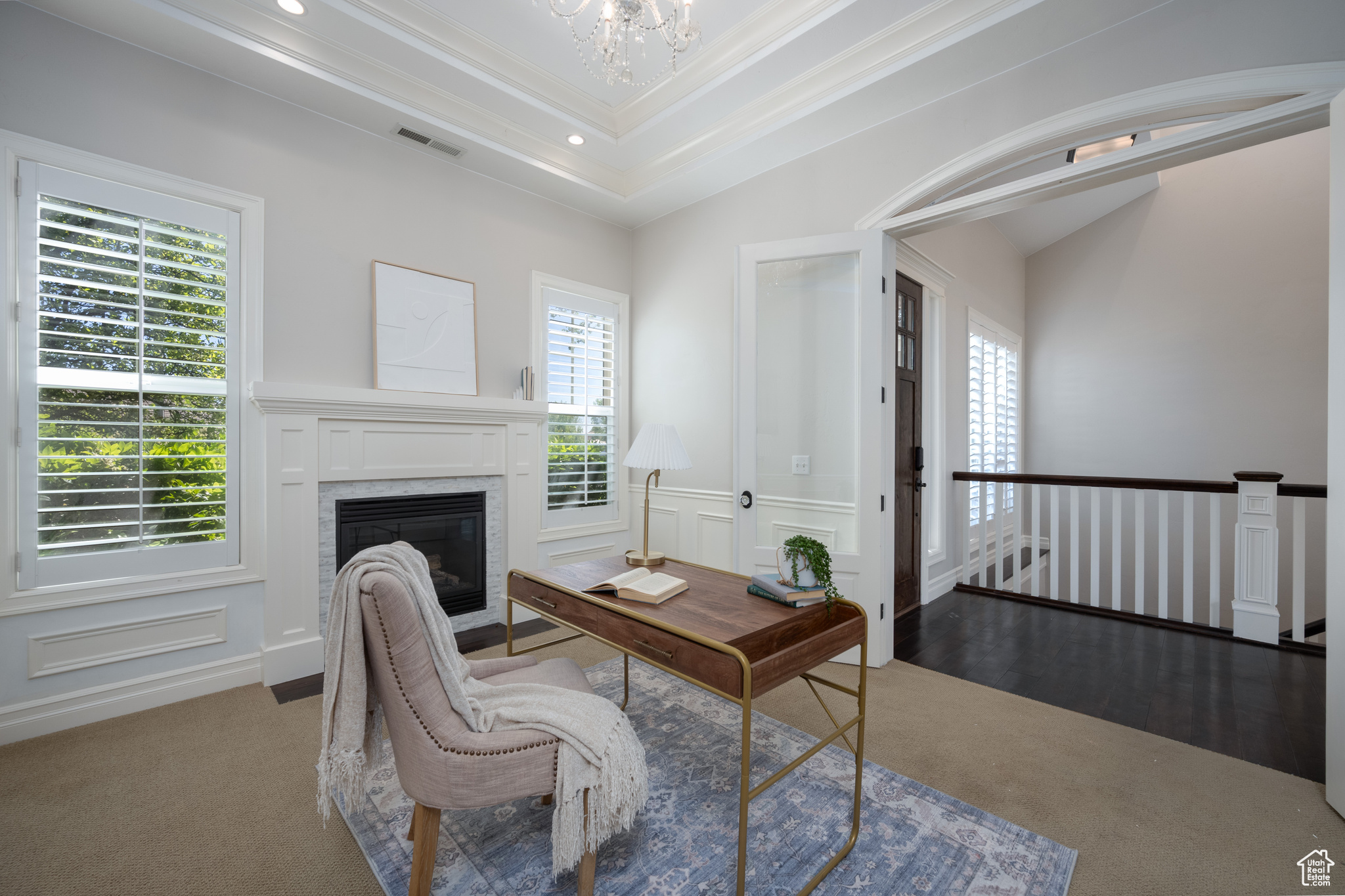 Carpeted office featuring a healthy amount of sunlight, a notable chandelier, a raised ceiling, and crown molding