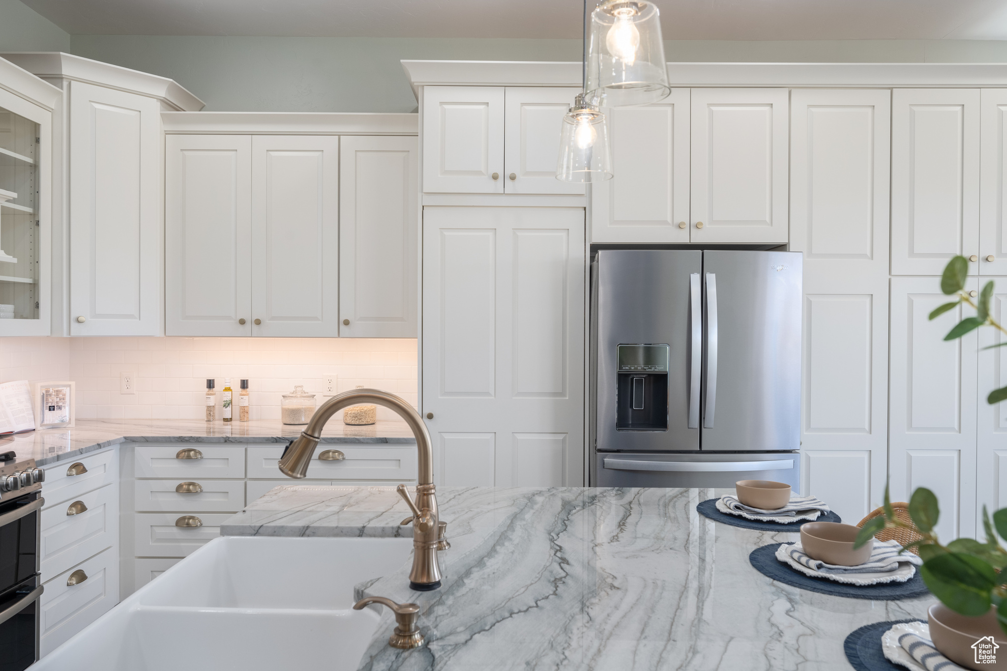 Kitchen with appliances with stainless steel finishes, white cabinetry, and pendant lighting