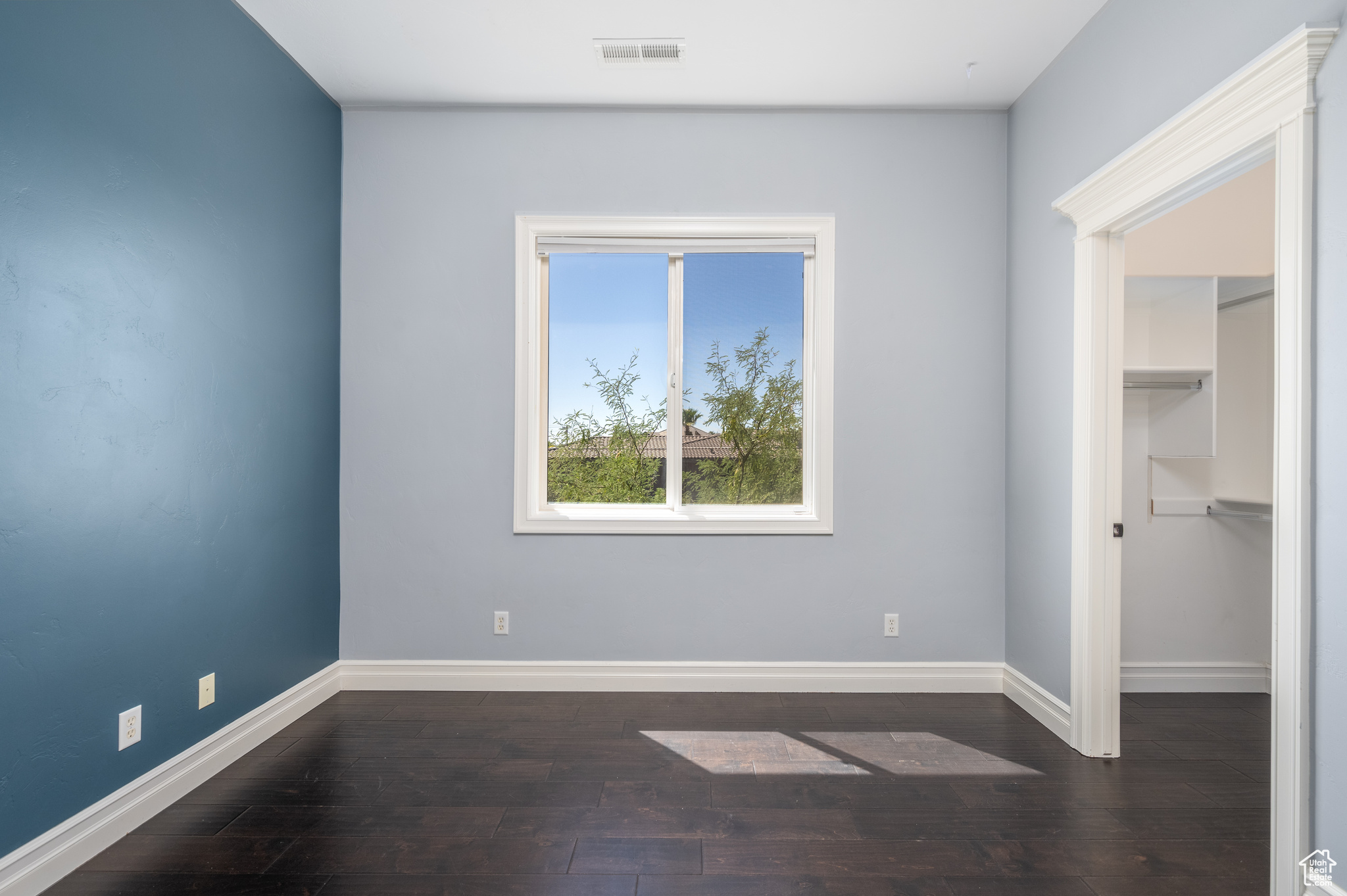 Unfurnished bedroom featuring a spacious closet and hardwood / wood-style floors