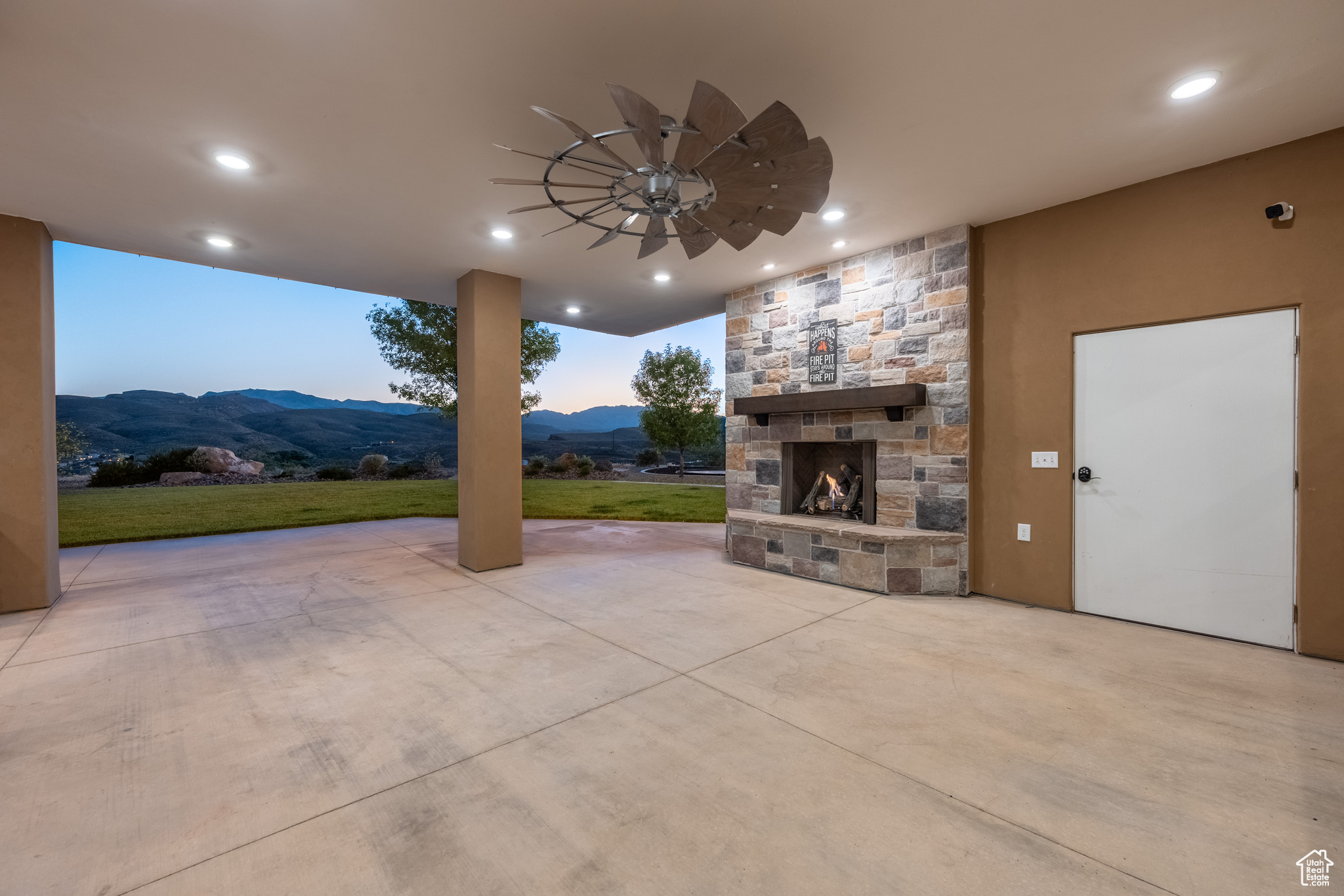 Patio terrace at dusk featuring an outdoor stone fireplace and a mountain view