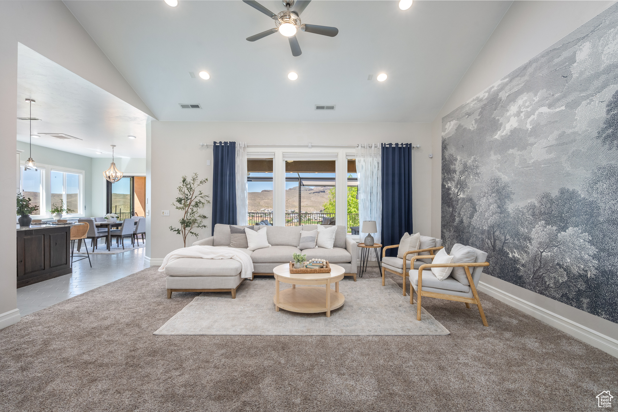 Living room with vaulted ceiling, carpet floors, and ceiling fan with notable chandelier