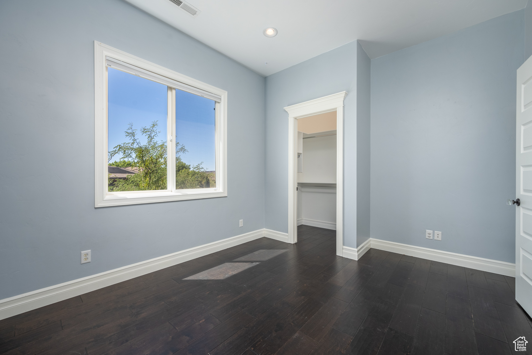 Unfurnished bedroom featuring dark hardwood / wood-style floors, a closet, and a walk in closet