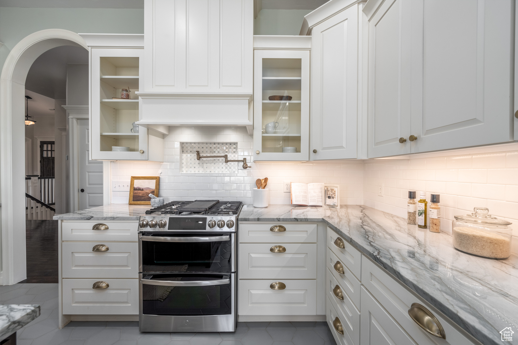 Kitchen with double oven range, tasteful backsplash, and light tile floors