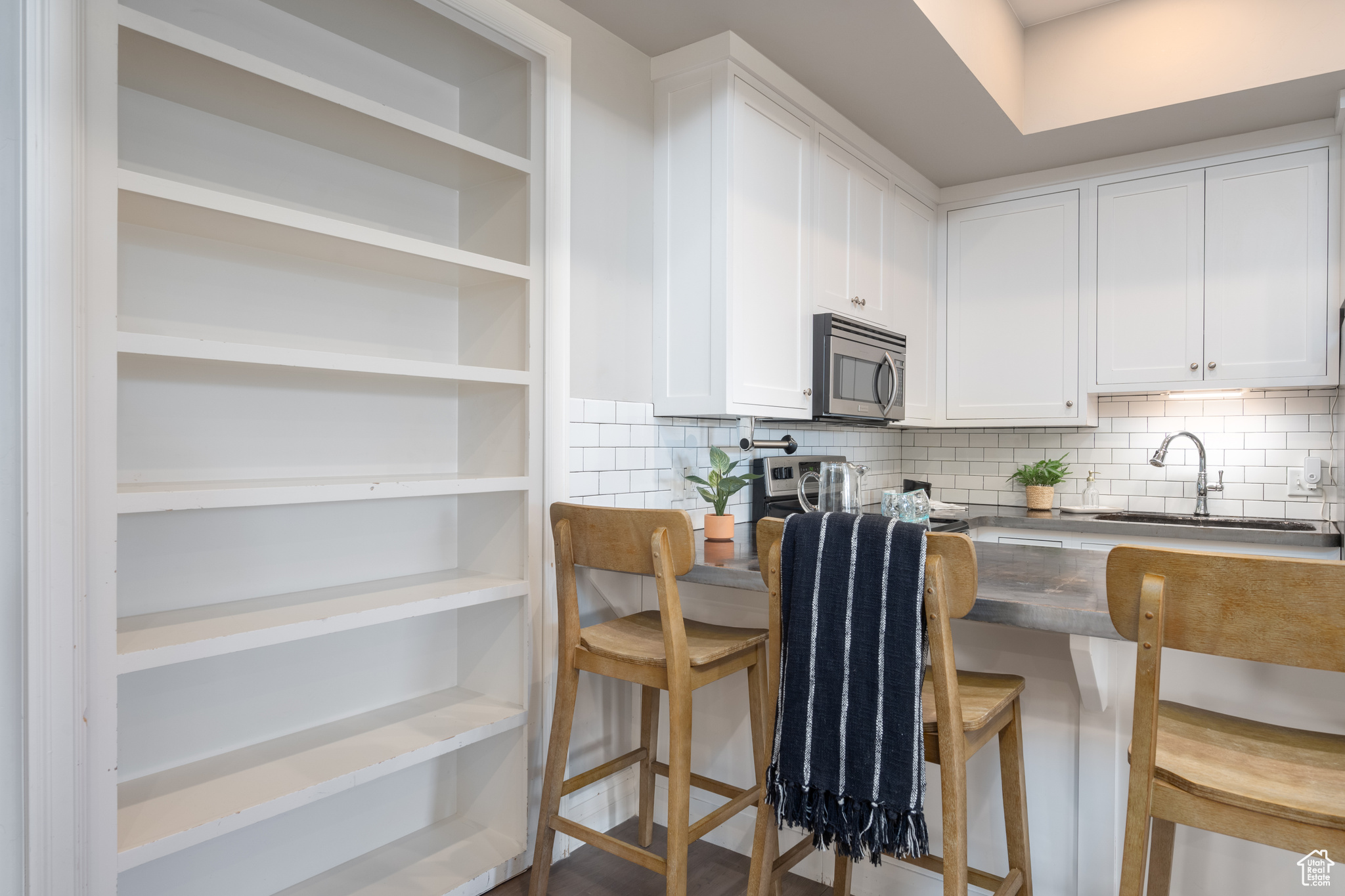 Kitchen featuring backsplash, sink, white cabinetry, and a breakfast bar area