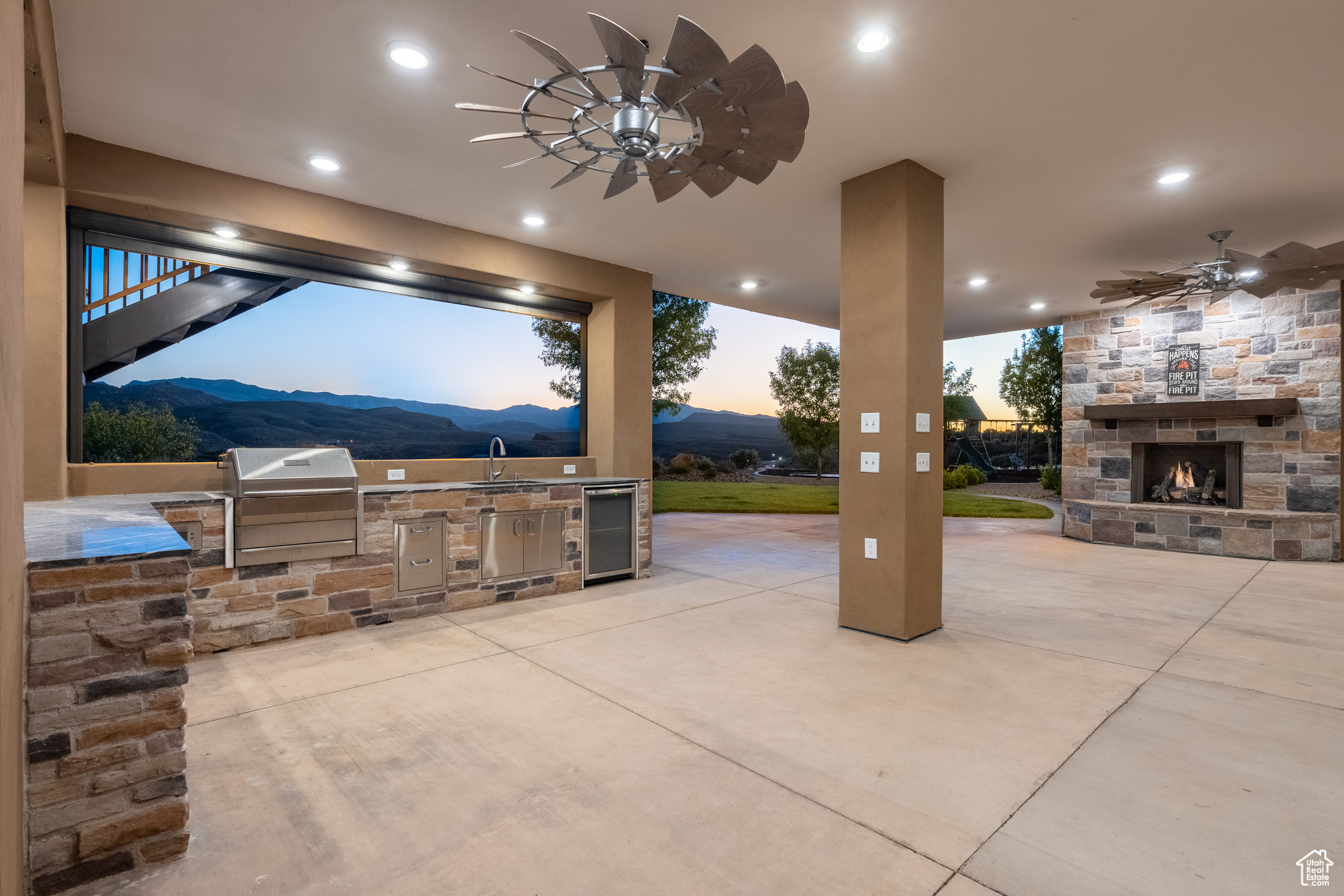 Patio terrace at dusk with grilling area, exterior kitchen, a mountain view, and ceiling fan