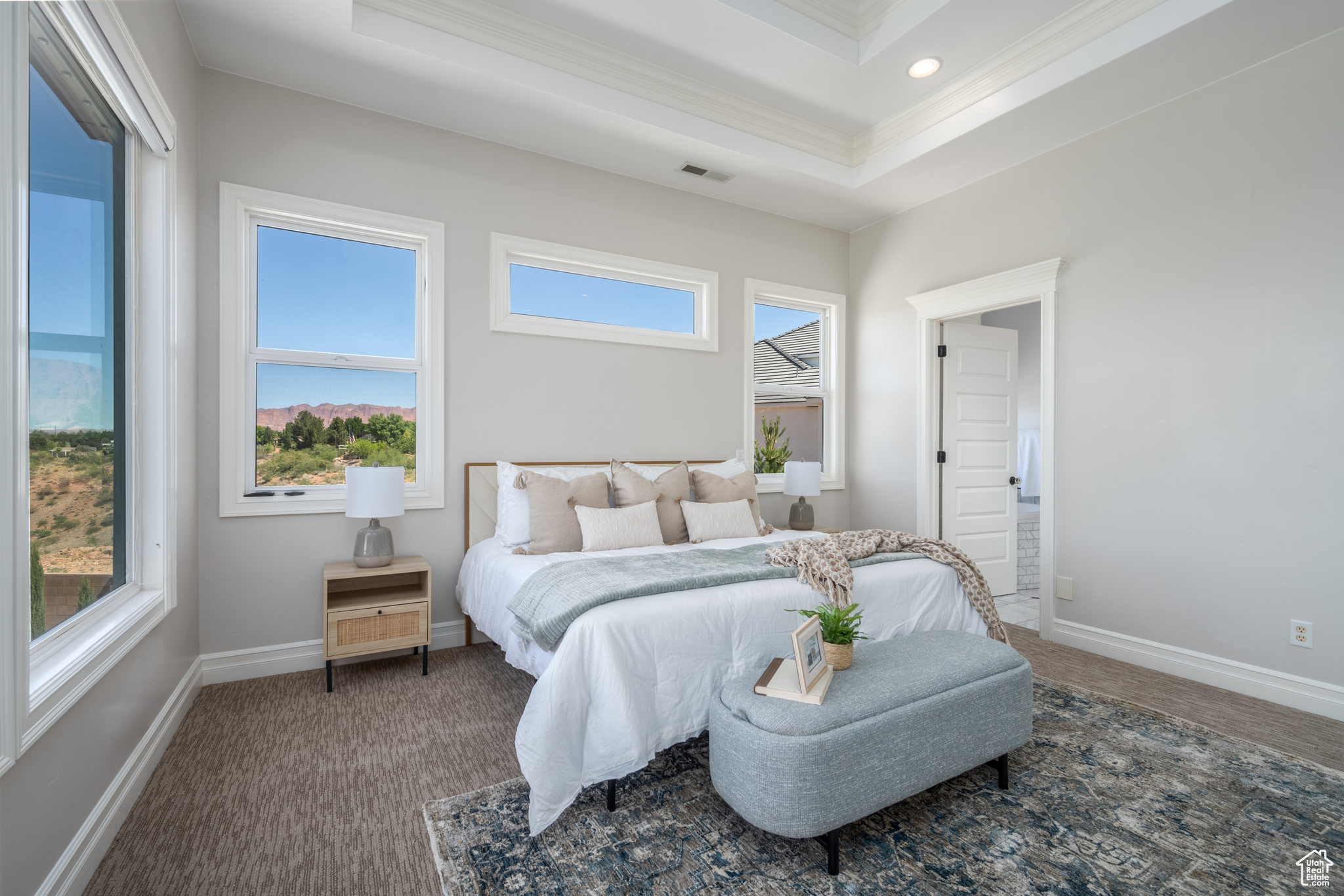 Bedroom with a tray ceiling, crown molding, and carpet flooring