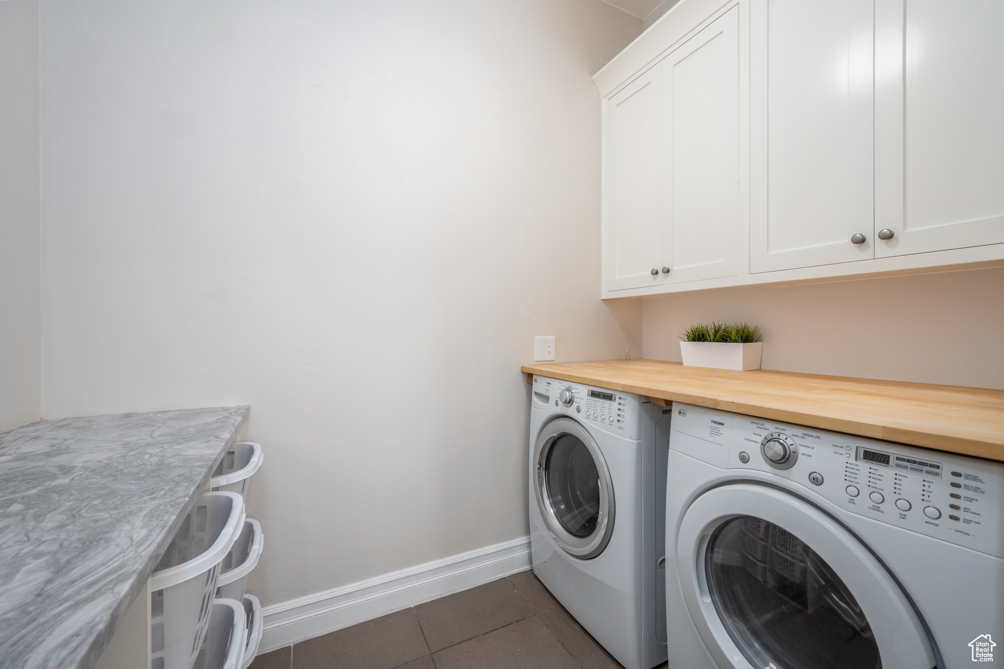 Washroom with cabinets, dark tile floors, and washing machine and clothes dryer