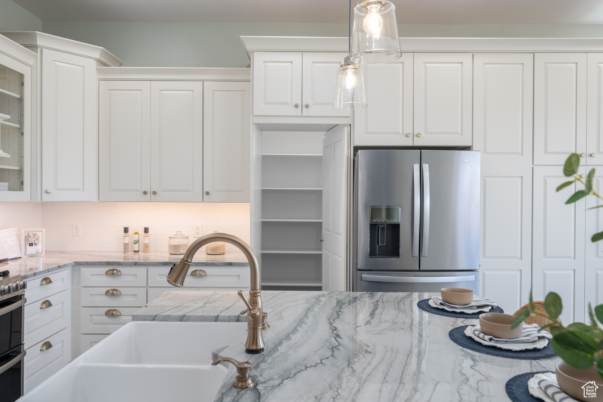 Kitchen with white cabinets, appliances with stainless steel finishes, and pendant lighting