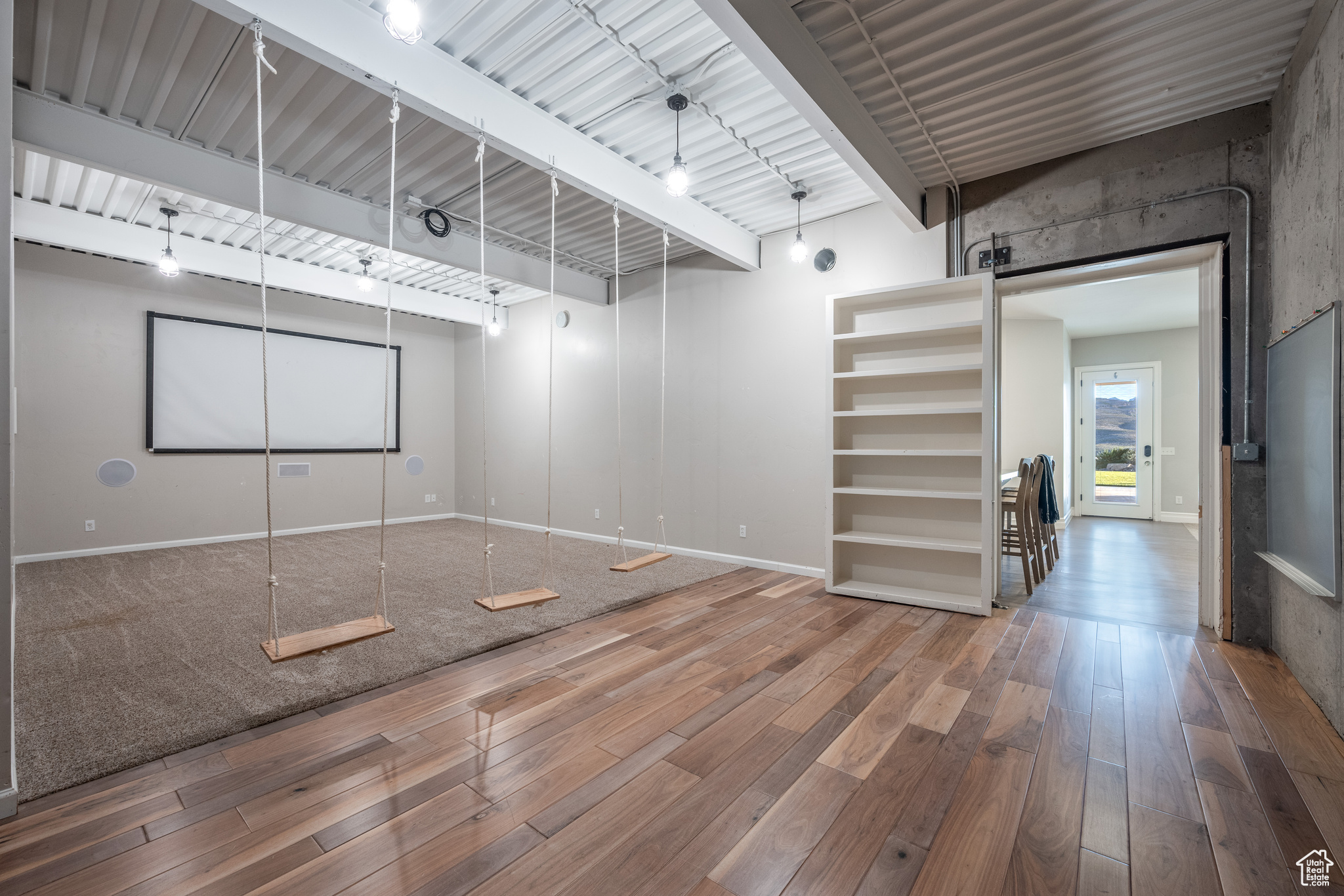 Empty room with beam ceiling, a barn door, rail lighting, and hardwood / wood-style floors