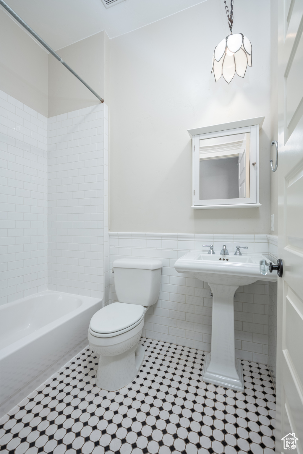 Bathroom with tiled shower / bath combo, tile flooring, toilet, and tile walls