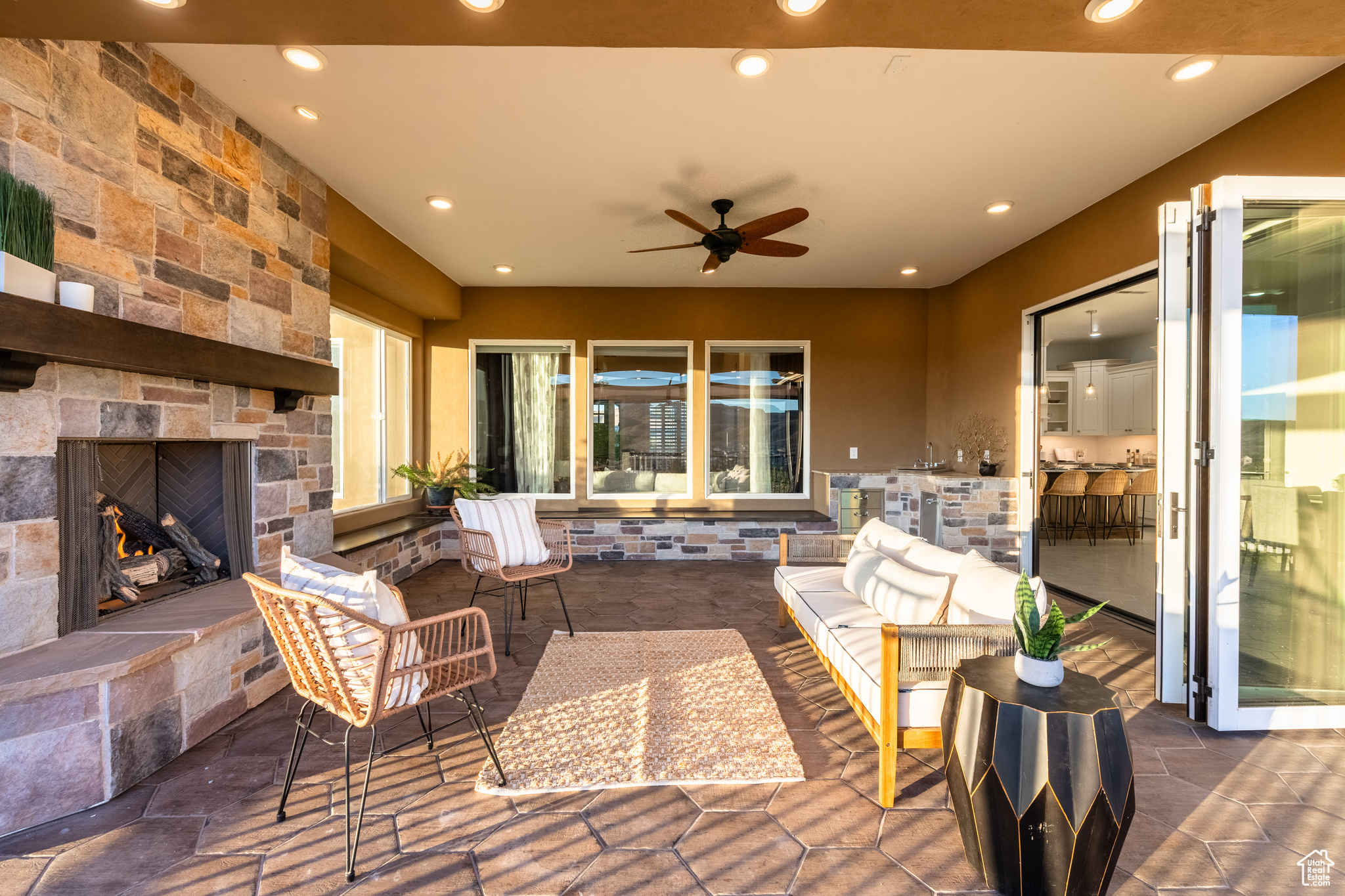 View of patio with a stone fireplace and ceiling fan