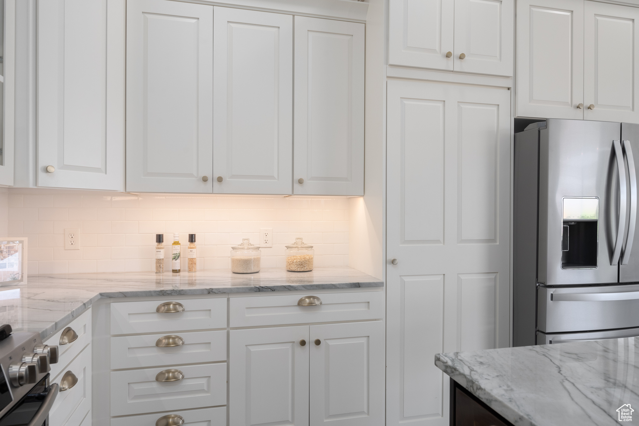 Kitchen featuring white cabinets, stainless steel fridge, and tasteful backsplash