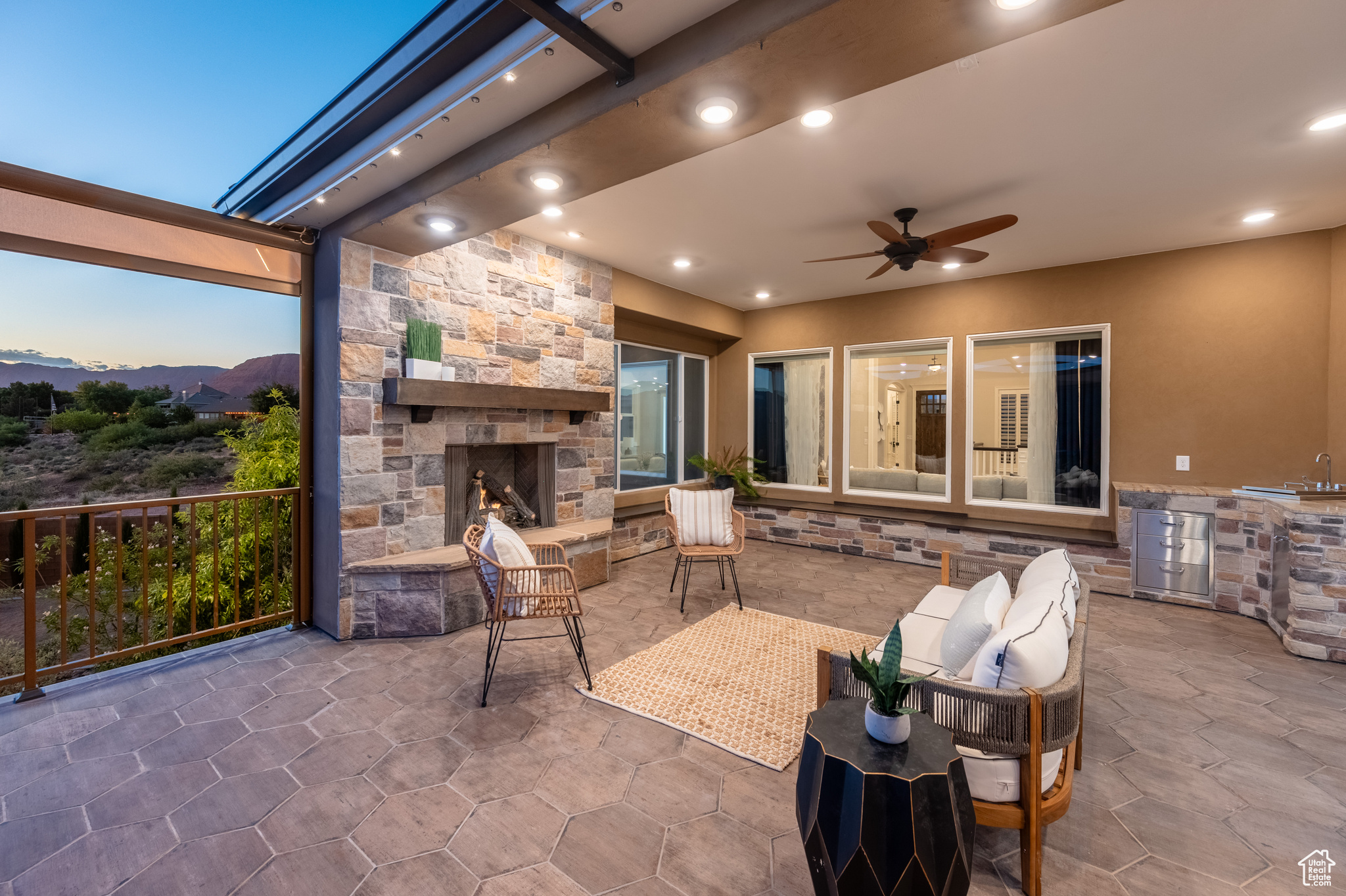 Patio terrace at dusk featuring ceiling fan and a fireplace