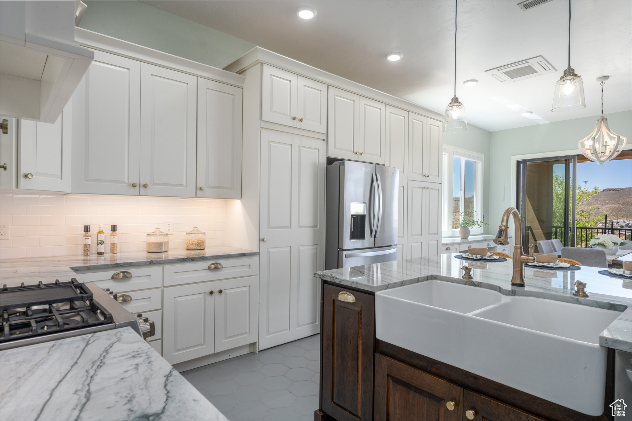 Kitchen with premium range hood, white cabinets, stainless steel refrigerator with ice dispenser, and backsplash