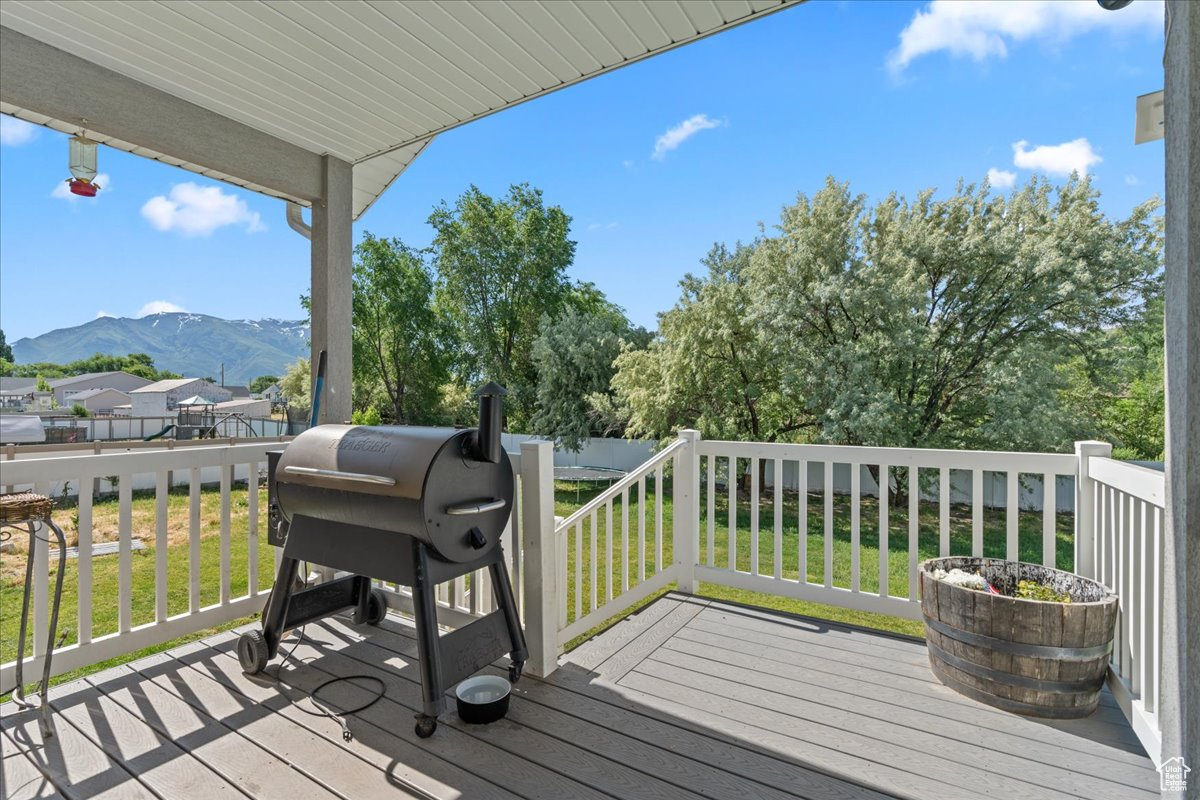 Deck with a lawn, a mountain view, and grilling area