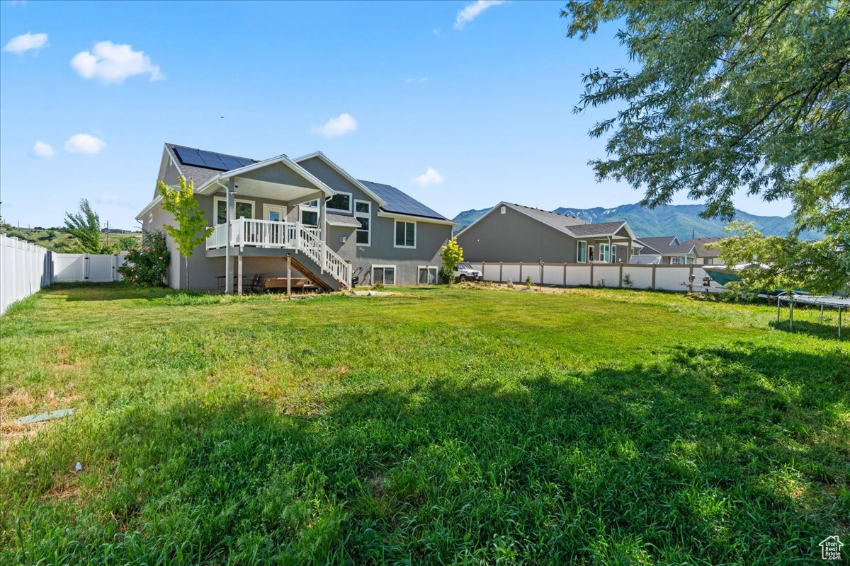 Rear view of property featuring a mountain view and a lawn