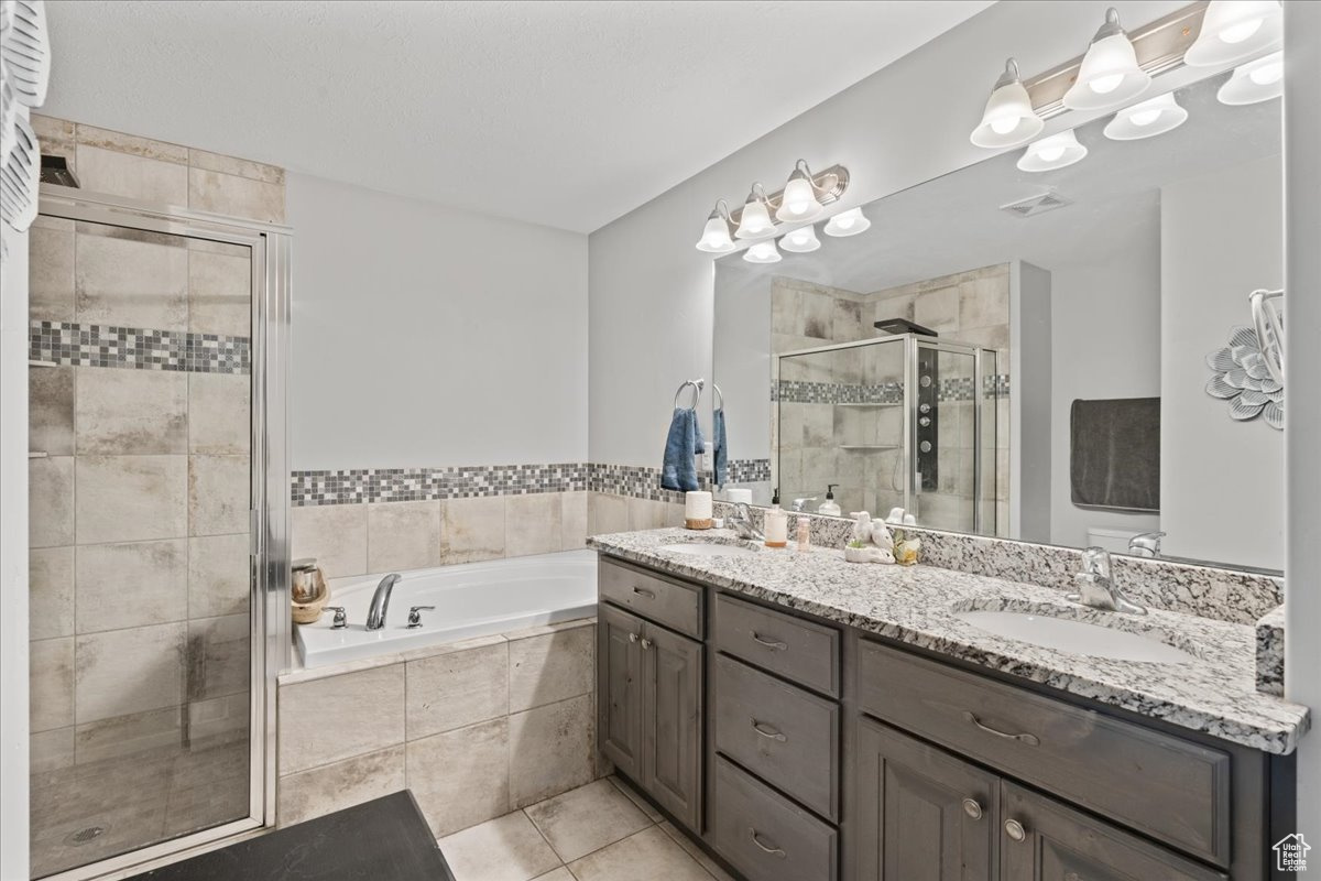 Bathroom with double vanity, tile flooring, and plus walk in shower