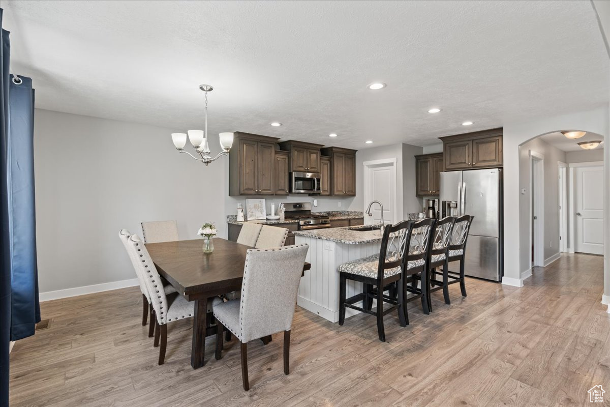 Dining space featuring sink, light wood-type flooring, and a chandelier