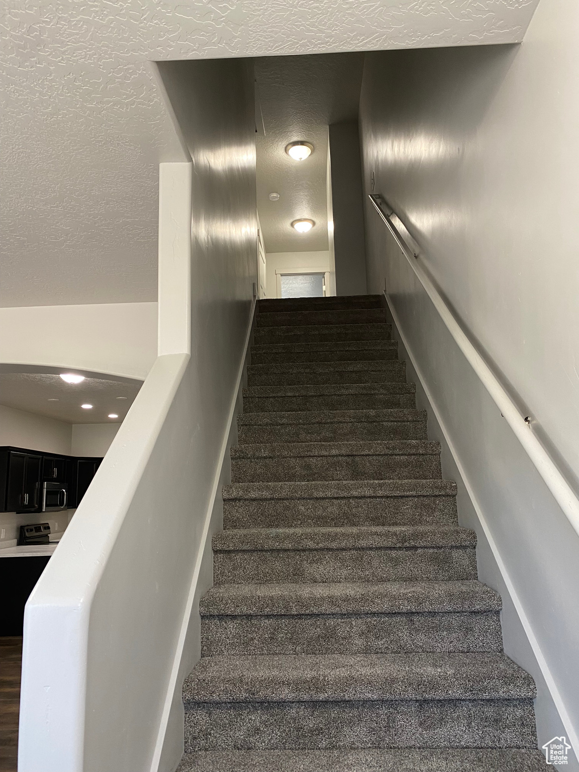 Staircase featuring a textured ceiling