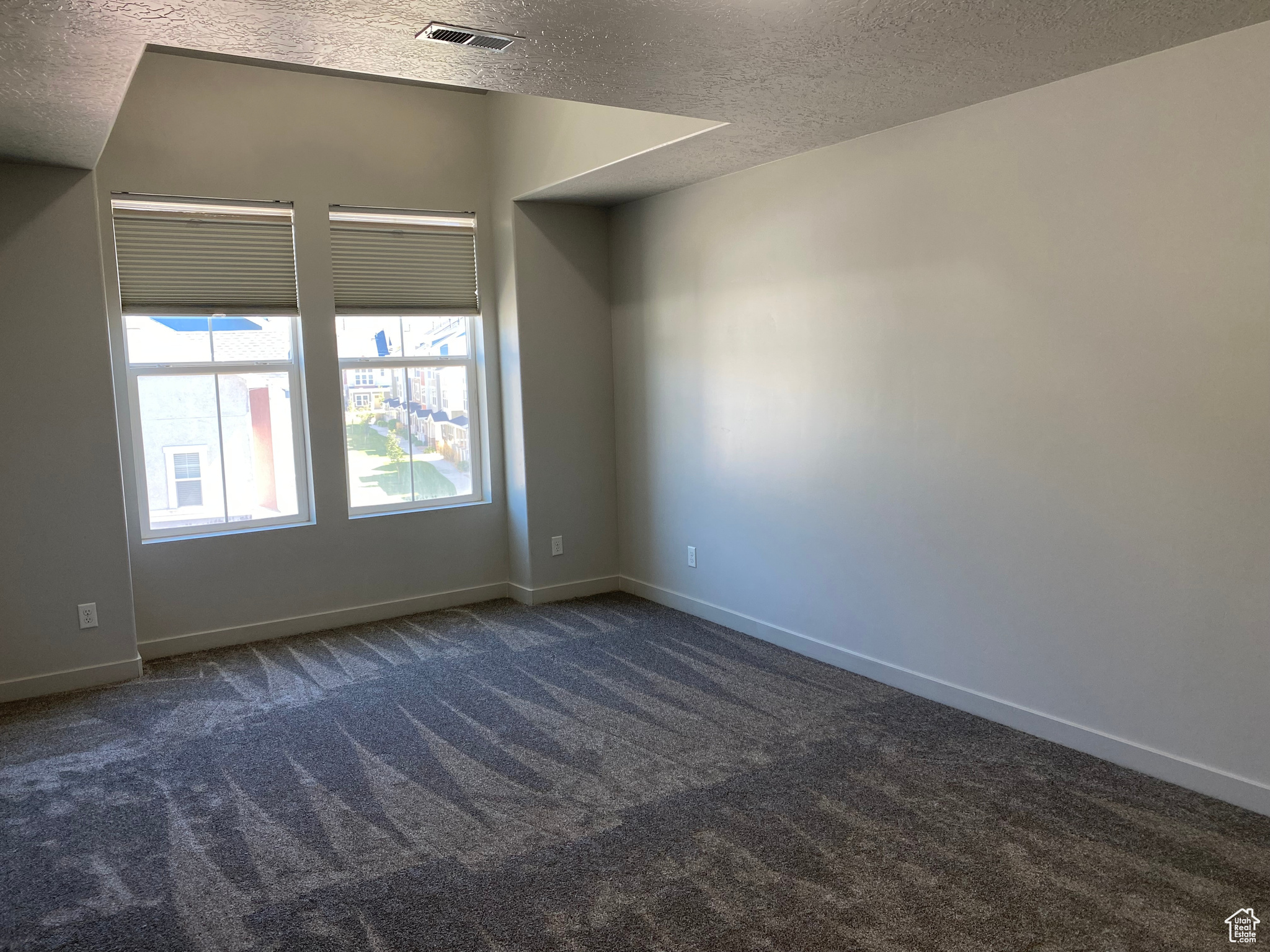 Carpeted empty room featuring a textured ceiling