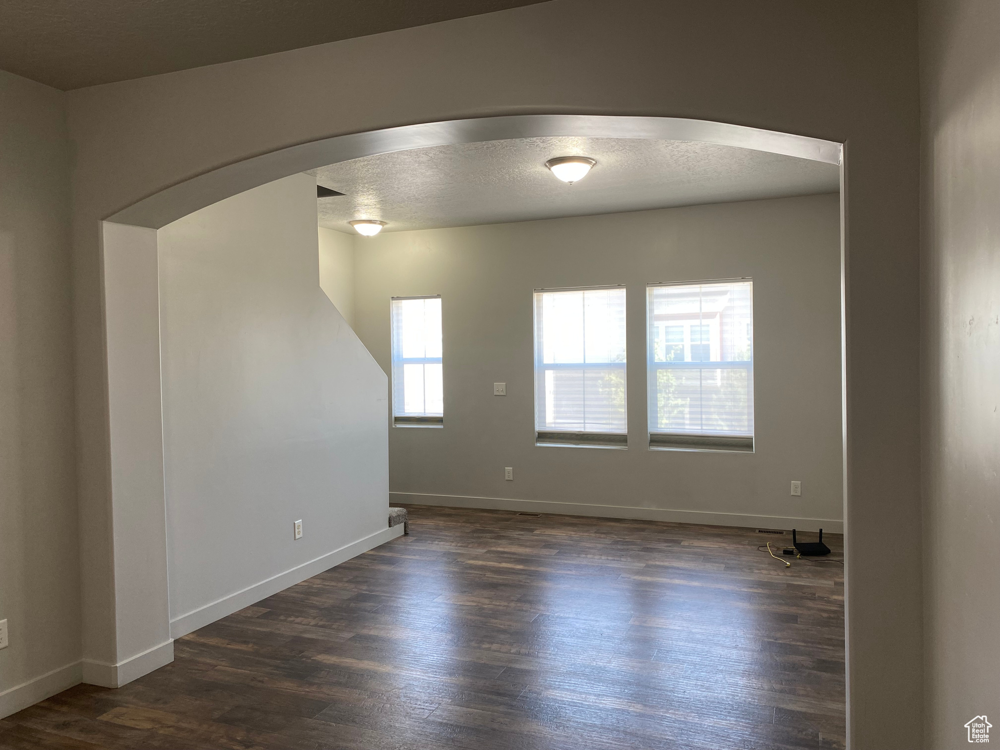 Spare room featuring a textured ceiling and dark hardwood / wood-style flooring