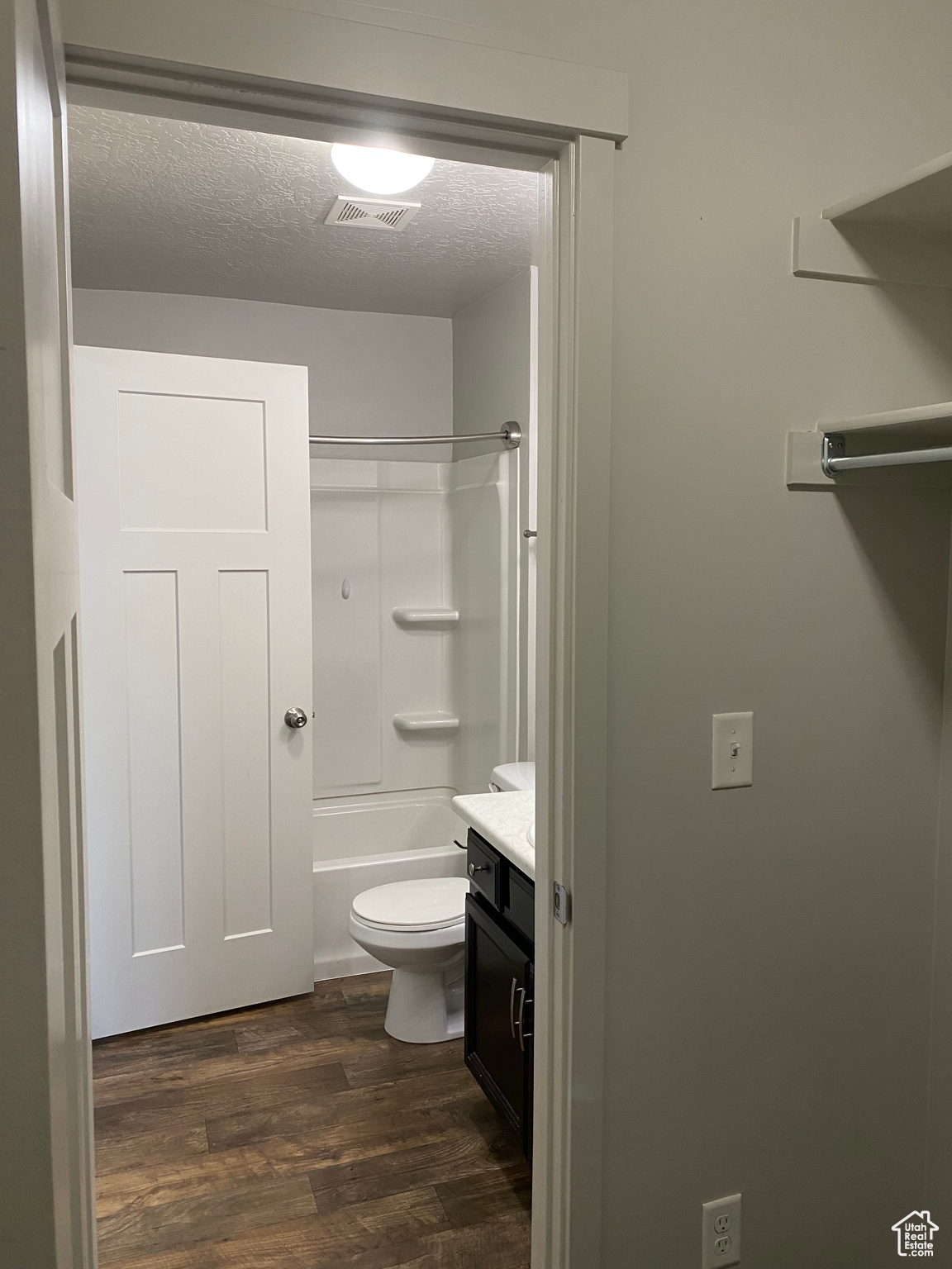 Full bathroom featuring vanity, shower / bath combination, wood-type flooring, a textured ceiling, and toilet