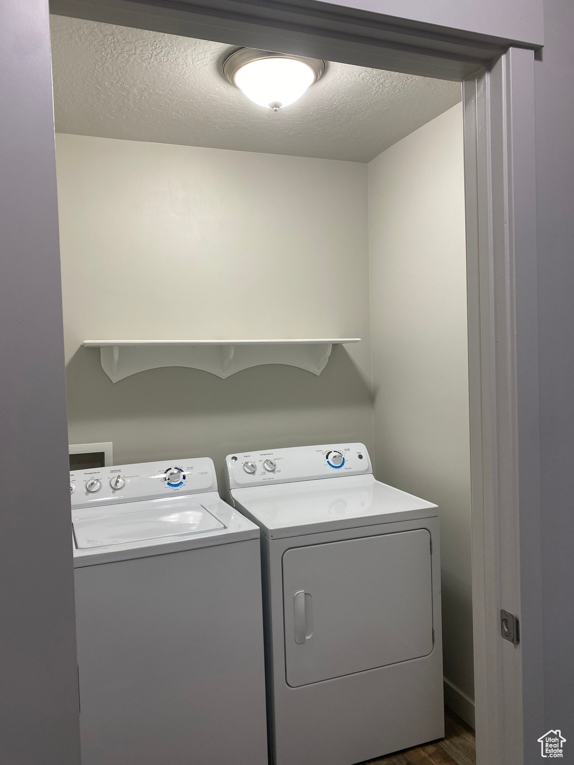 Laundry room with a textured ceiling, dark wood-type flooring, and washing machine and clothes dryer