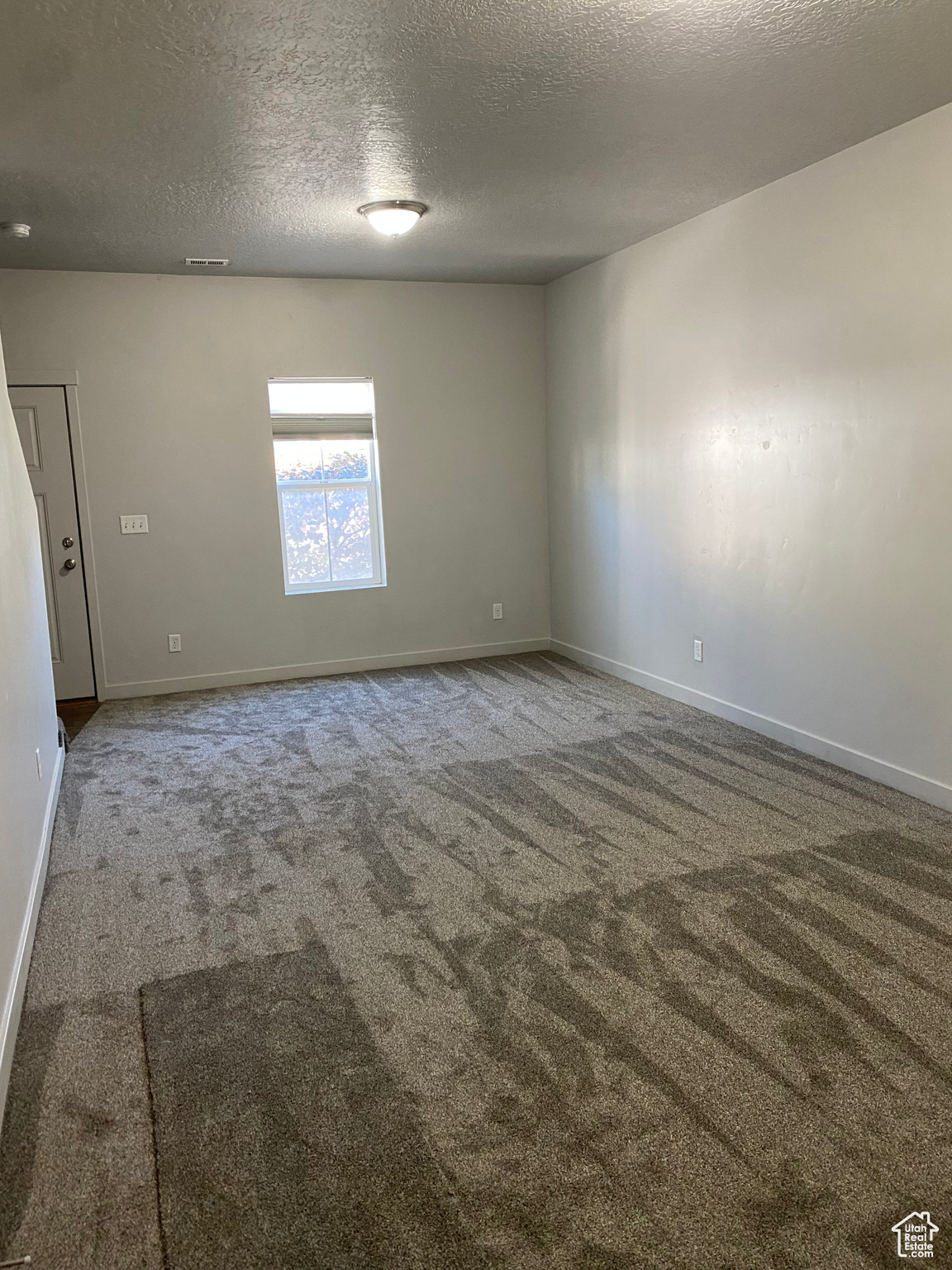 Unfurnished room with a textured ceiling and carpet