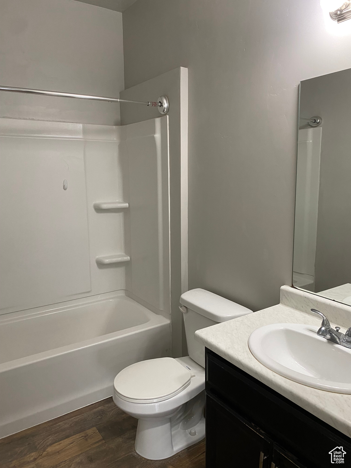 Full bathroom featuring vanity, toilet, washtub / shower combination, and hardwood / wood-style flooring