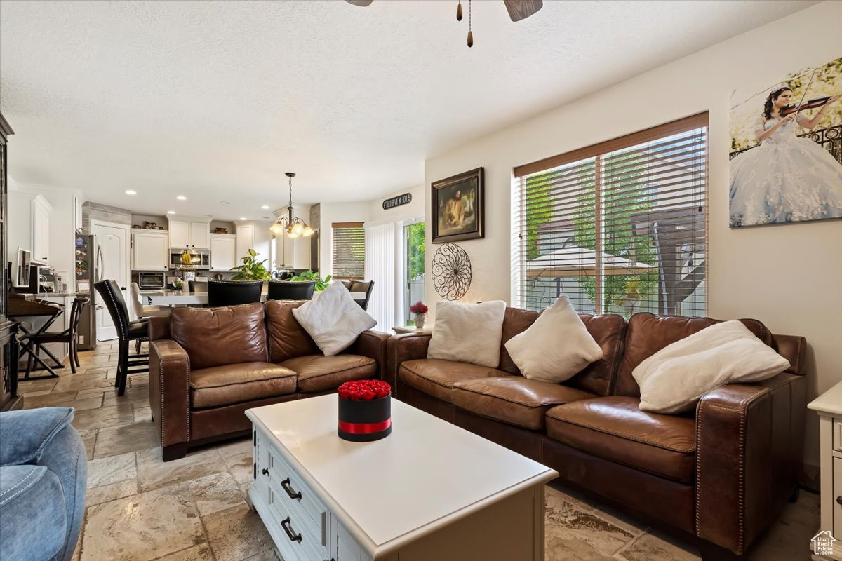 Tiled living room with ceiling fan with notable chandelier