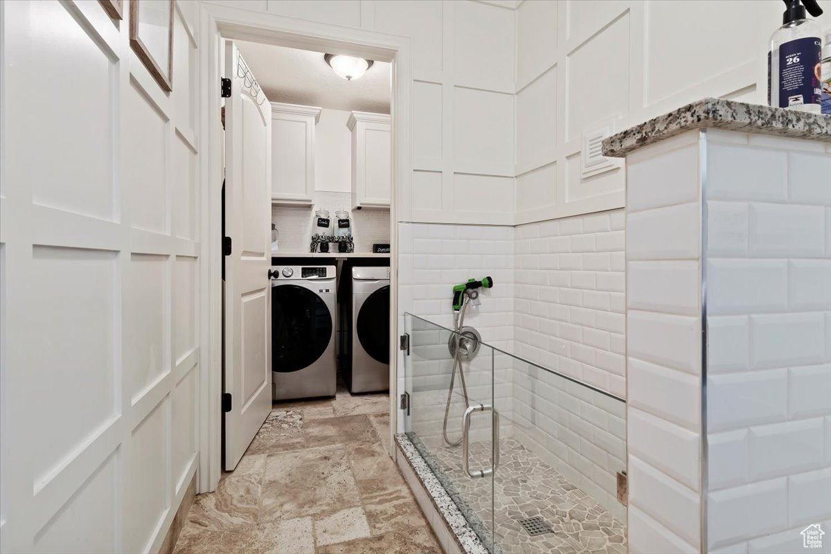 Laundry room with cabinets, washing machine and clothes dryer, and light tile patterned floors