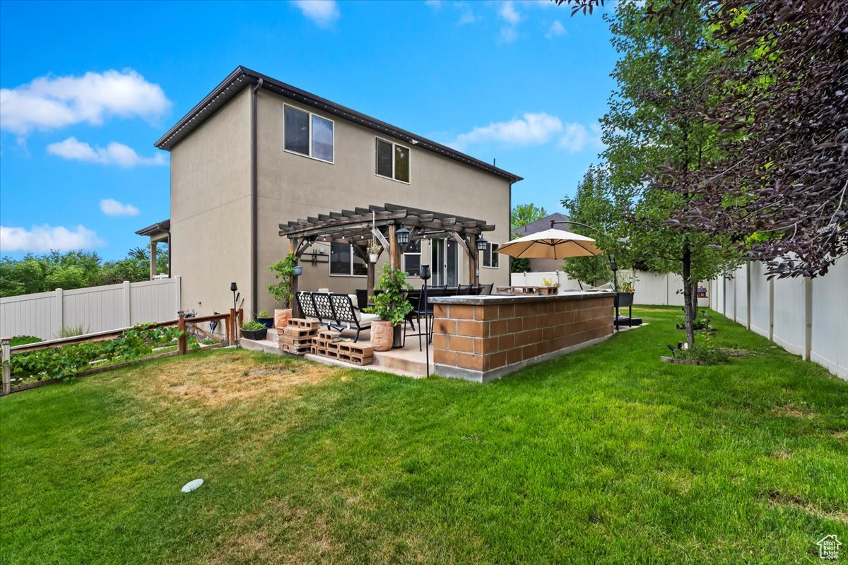 Rear view of property with a patio, a lawn, and a pergola